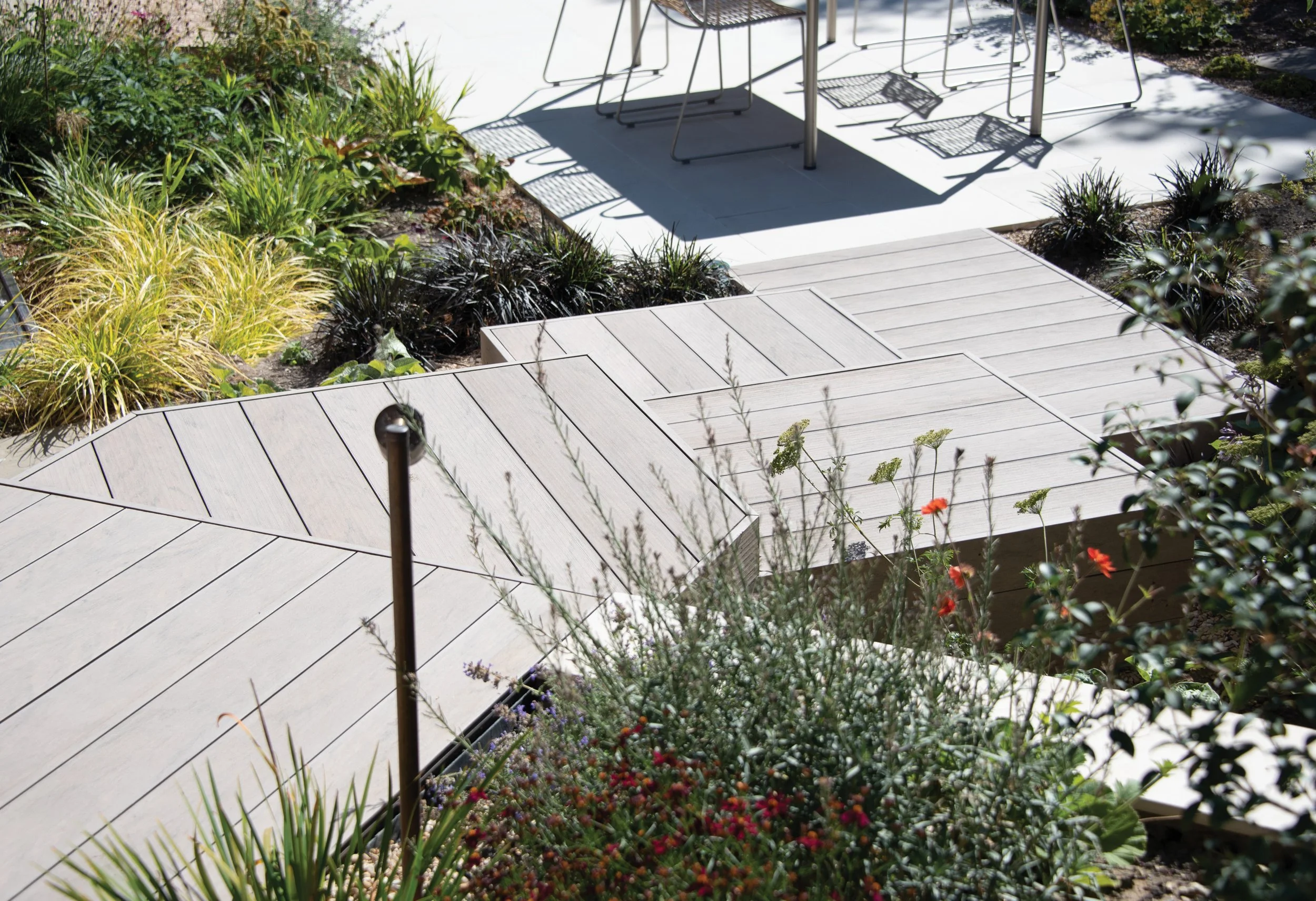Detailed contemporary japanese influenced composite decking steps, surrounded by grasses and flowering perennial planting.