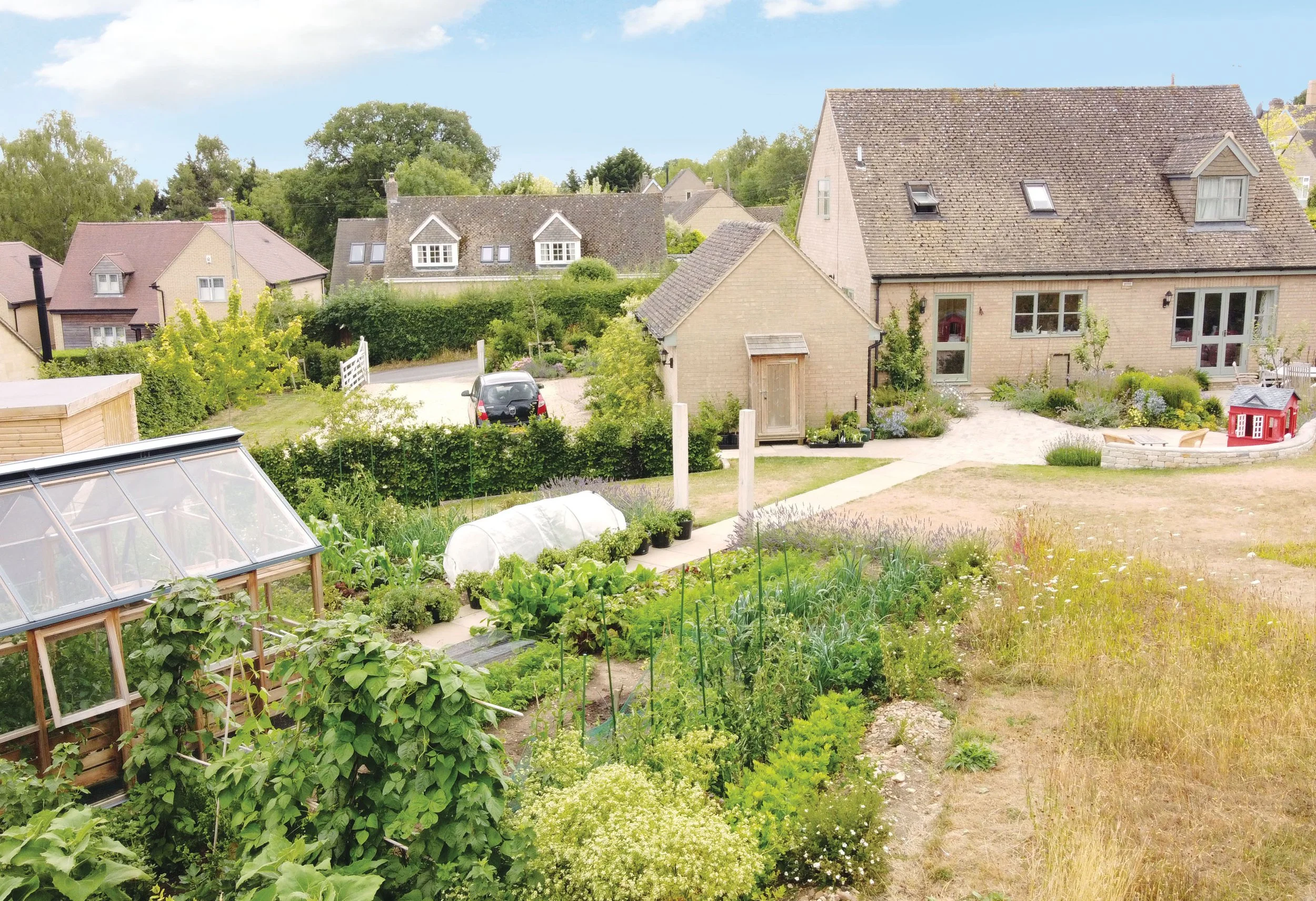 Aerial view from the productive garden back towards the house, showing vegetable beds, planting, meadow and the relationship between the garden spaces.