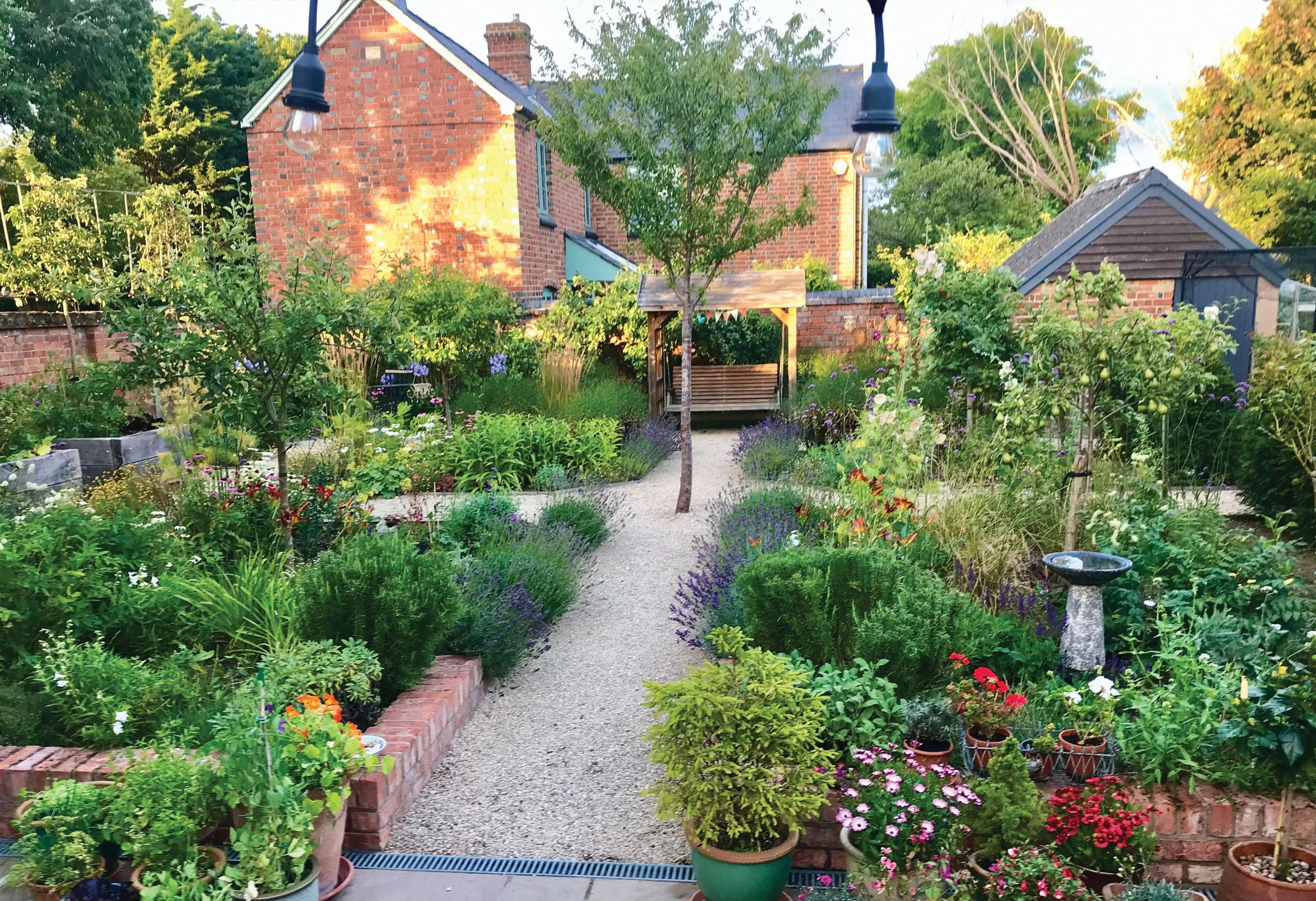 Cherry tree at the centre of the formal quad, surrounded by gravel paths and richly layered planting.