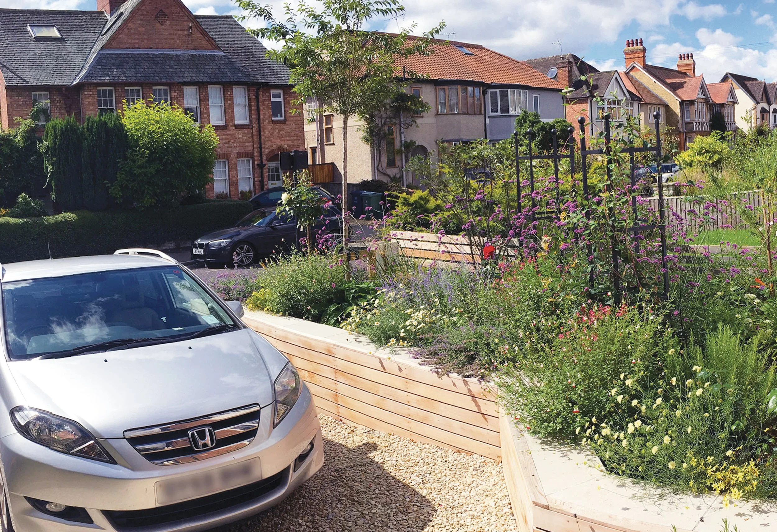 Small front garden combining raised cedar clad beds, gravel, perennial planting and informal productive growing.