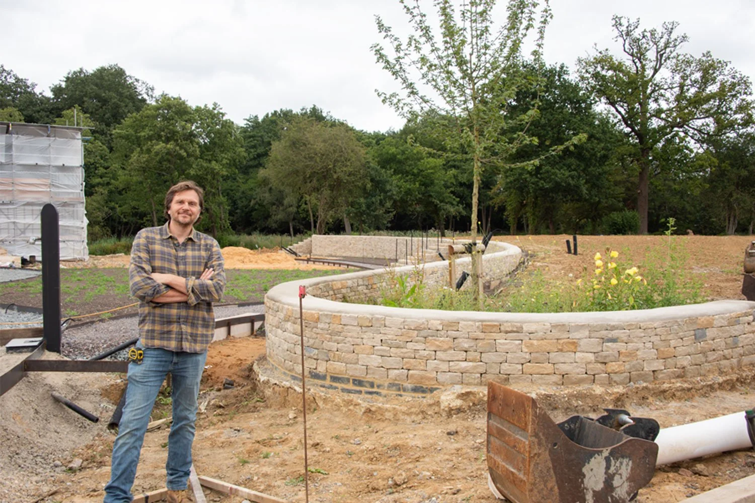 Doug Holloway on site during construction of a curved stone wall, reflecting a hands-on approach developed through more than 20 years of landscape design and construction experience.