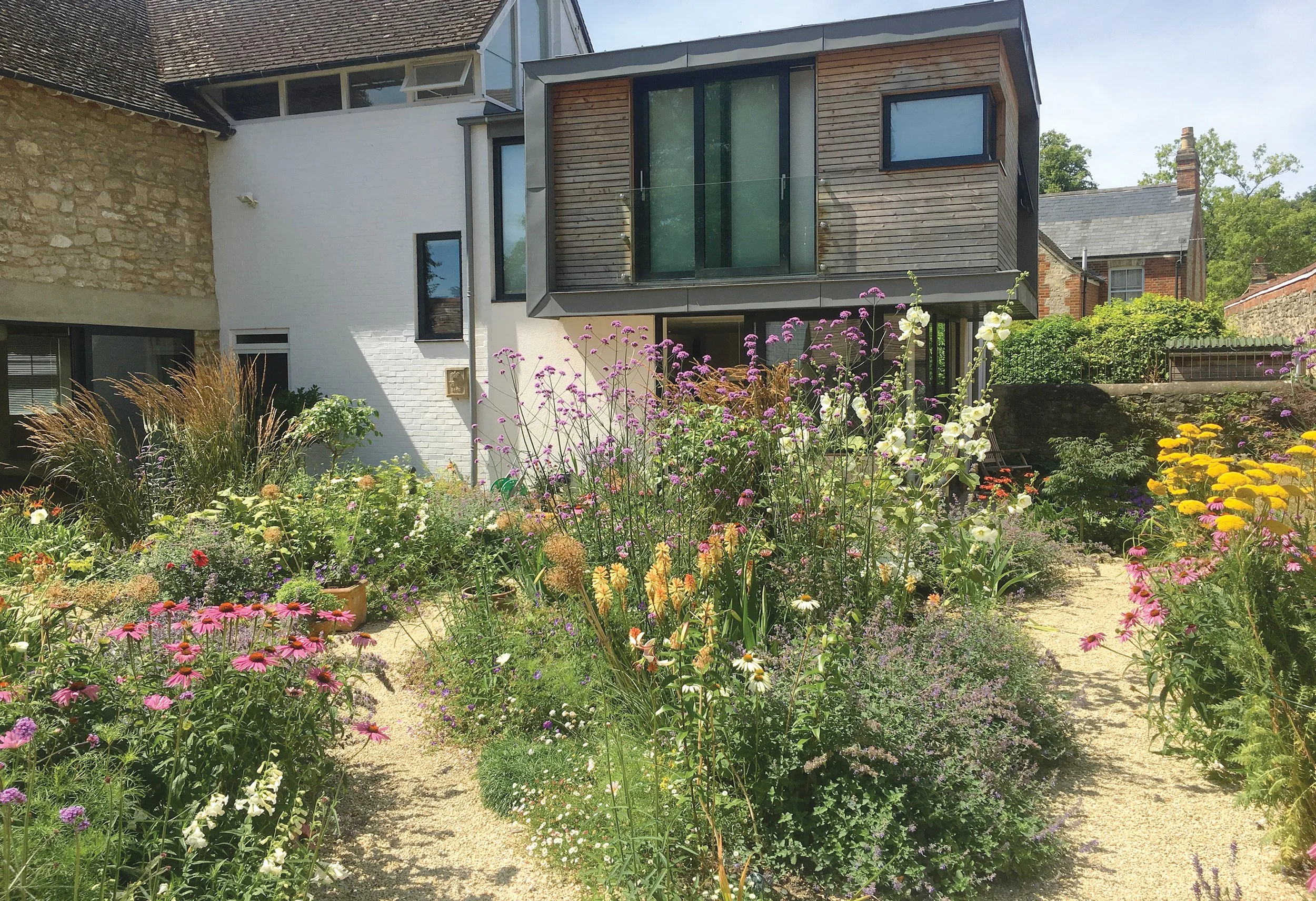 Naturalistic perennial planting surrounding a contemporary house extension and gravel garden.