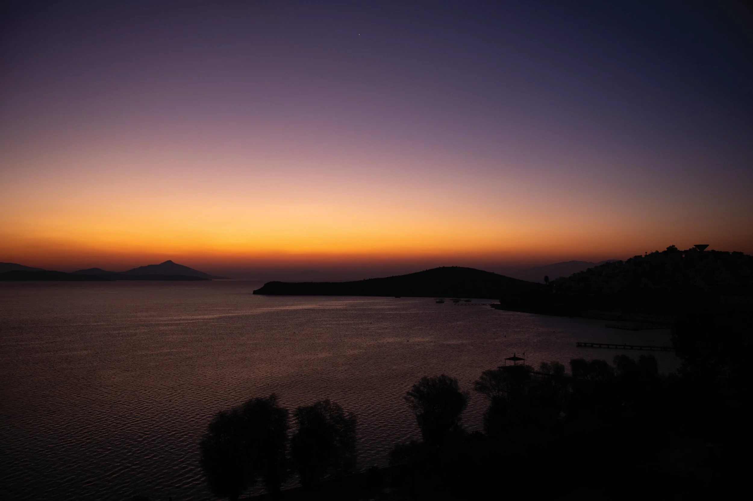 The first soft glow of daylight as the sun rises below the horizon.