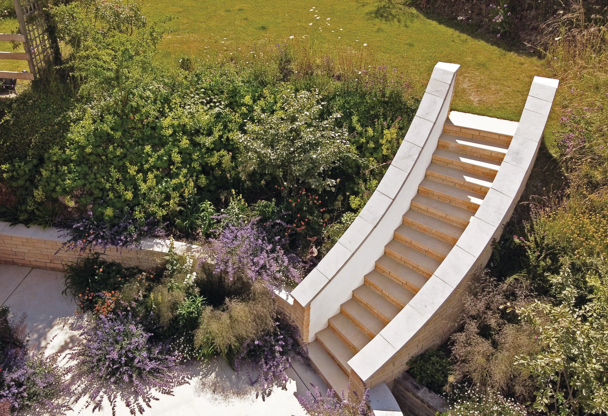 Aerial detail of the sculptural curved stone staircase surrounded by layered planting.