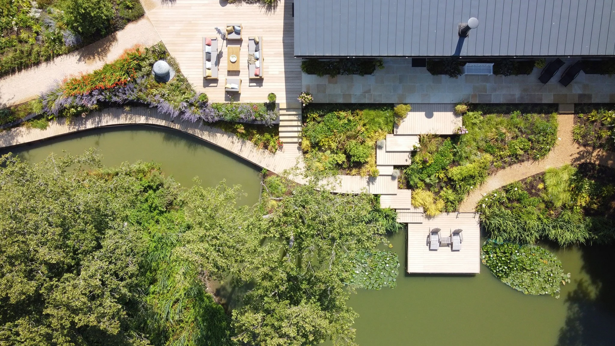 Overhead view of timber decks, waterside planting and lily pads connecting the house with the lake.
