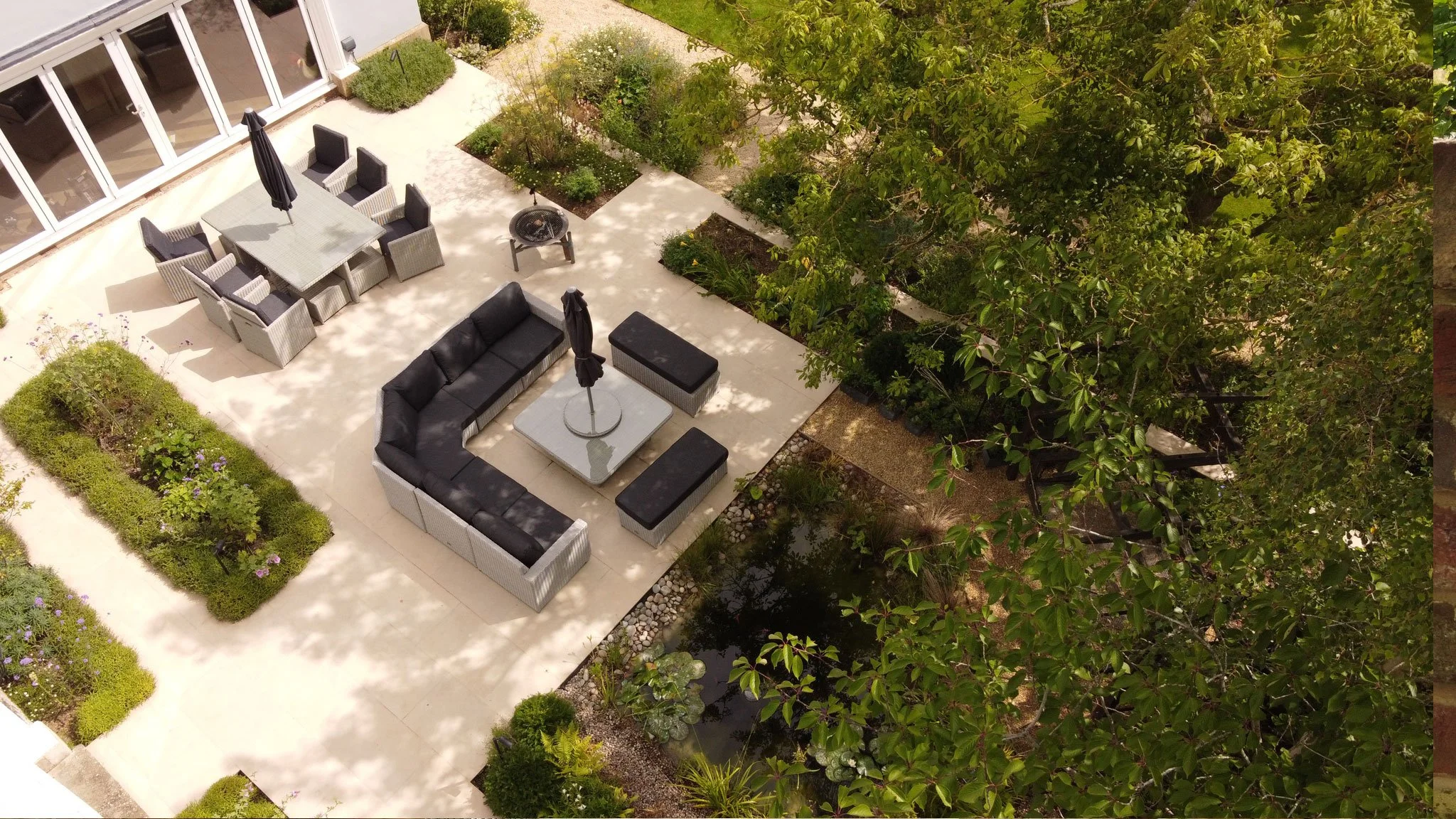 Contemporary outdoor seating beside a small garden pond, surrounded by naturalistic planting.