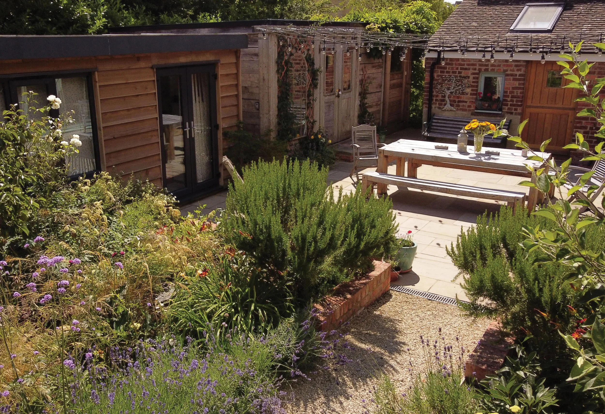 View back towards the paved courtyard, with raised heritage brick border and herbs closest to the kitchen.