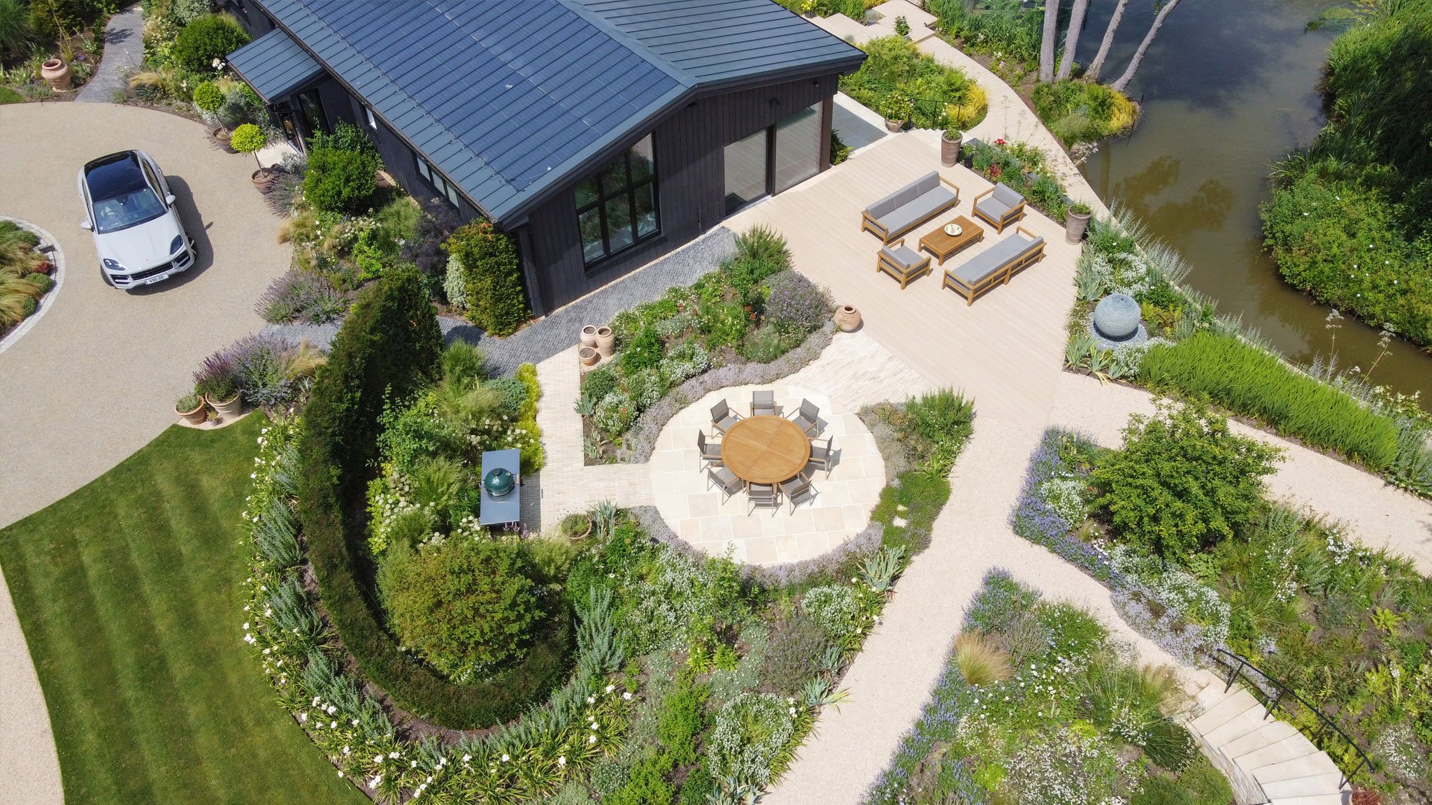 Aerial view of the main garden terraces, curved planting beds, spiralling planting concept, and outdoor seating beside The Lake House.