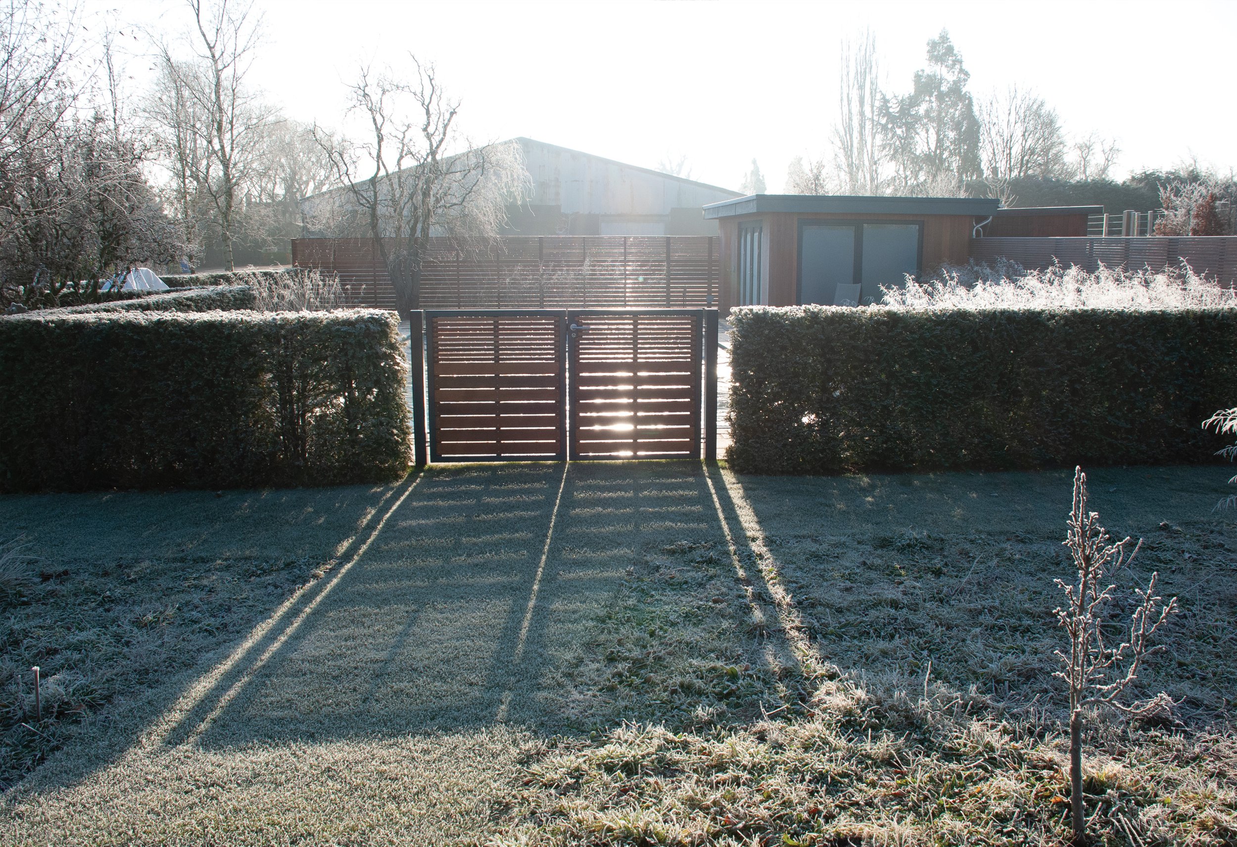 Bespoke cedar and metal gates and fencing enclosing the pool garden, photographed in winter.