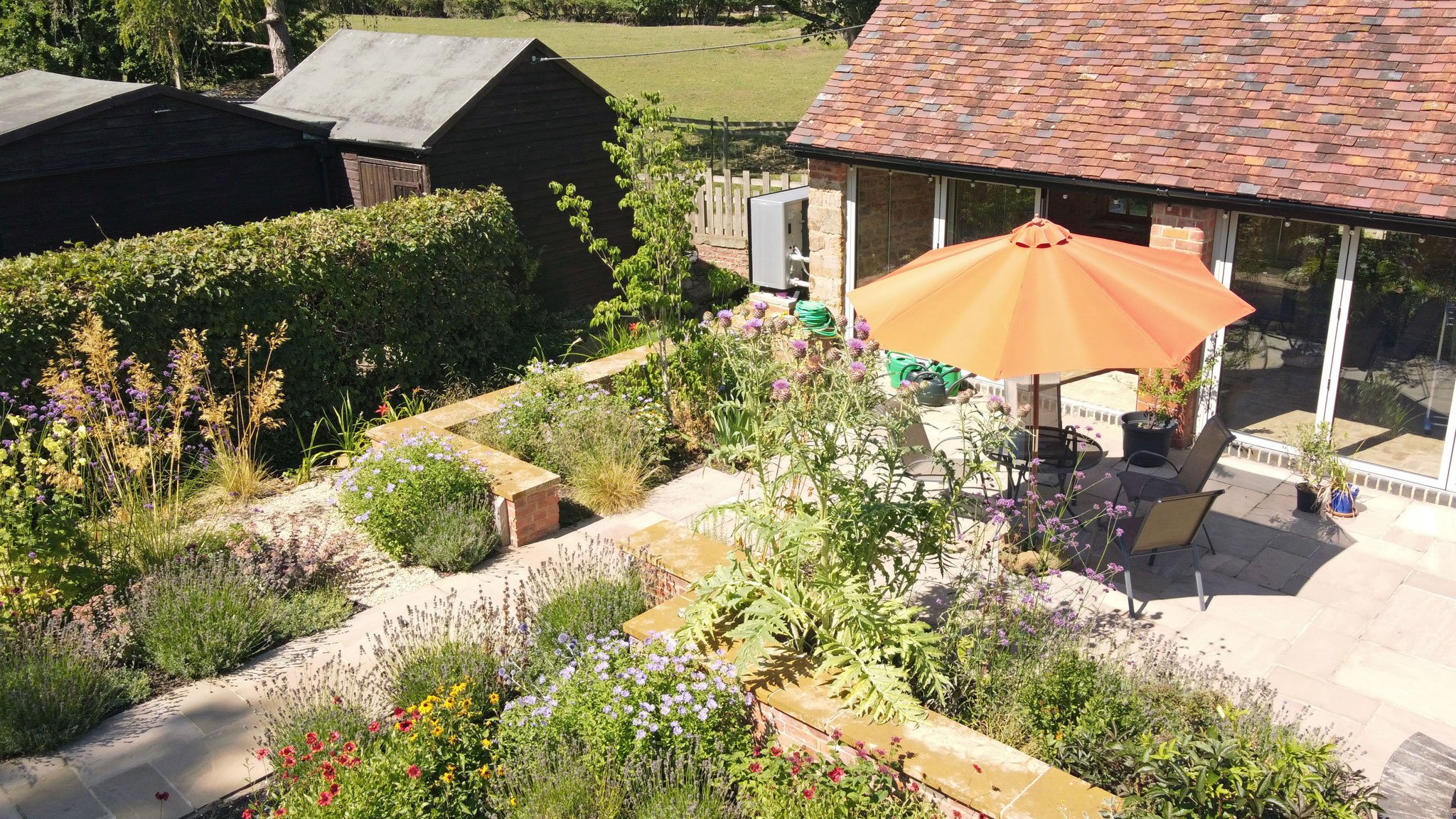 Enclosed courtyard seating area beside the converted barn, with low walls designed to incorporate temporary flood barriers when required.