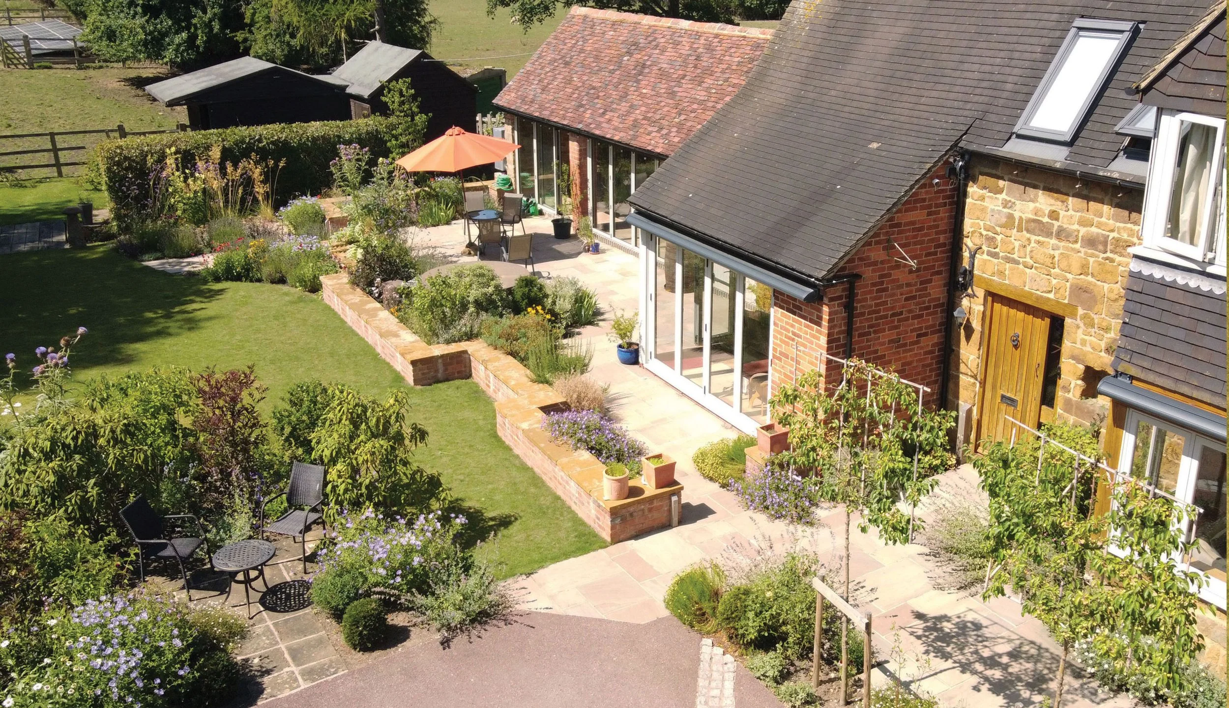 Aerial view of the converted barn and courtyard, with low walls, planting and seating integrated around the building.