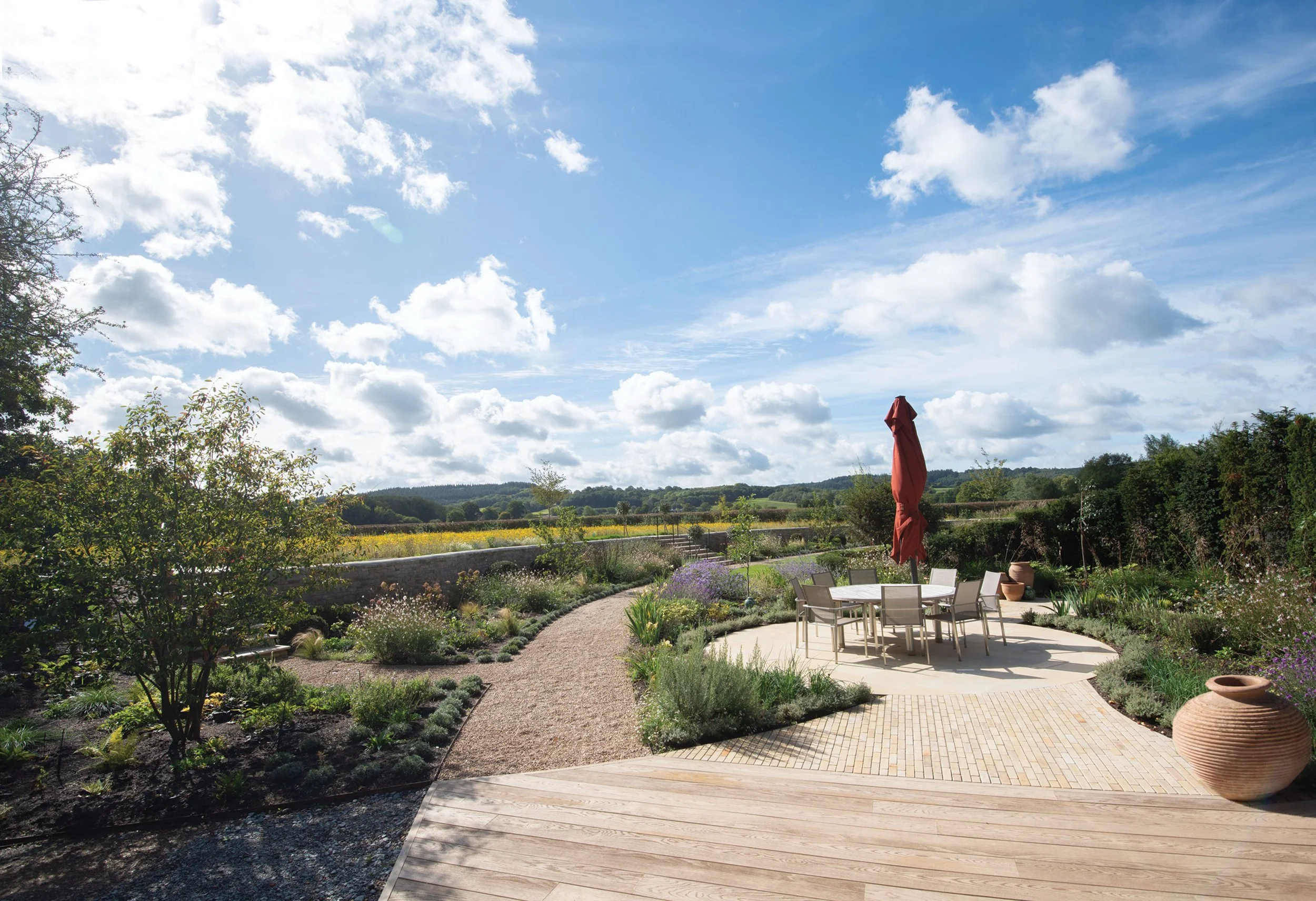 Curving garden paths and planting opening towards the wider landscape at The Lake House in Surrey.