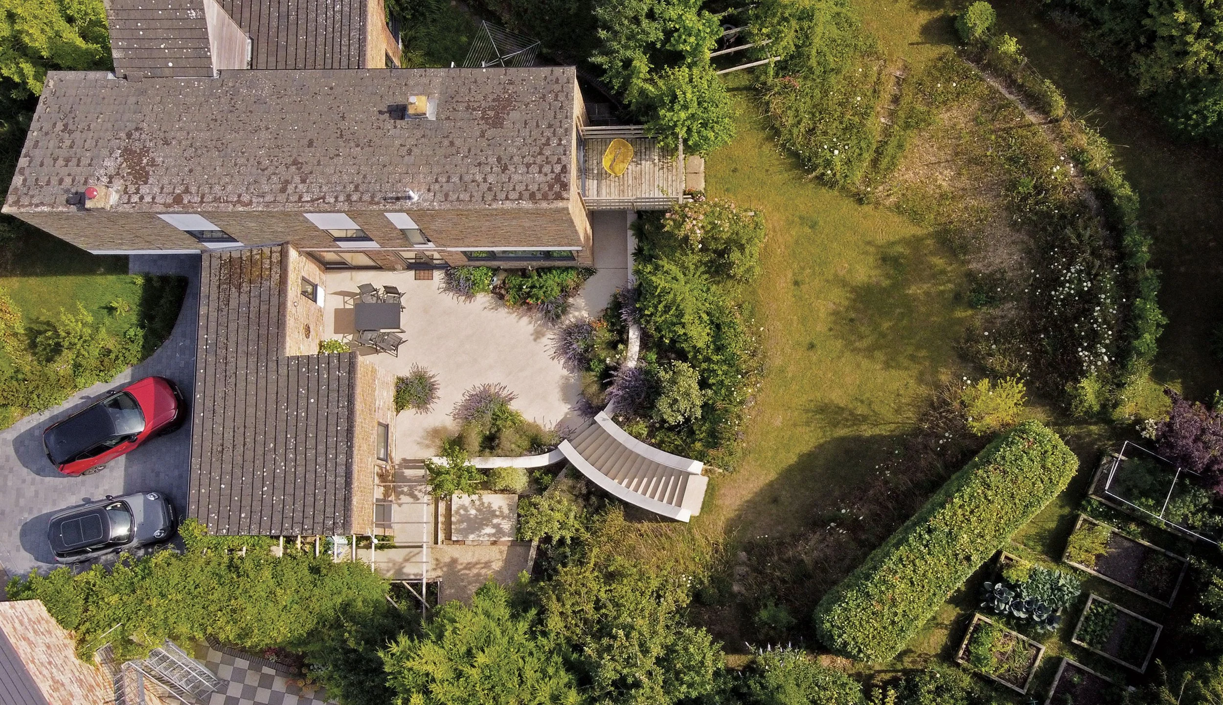 Aerial view of The Sunken Garden in Beckley, Oxfordshire, showing the house, curved steps, terraces and surrounding planting.