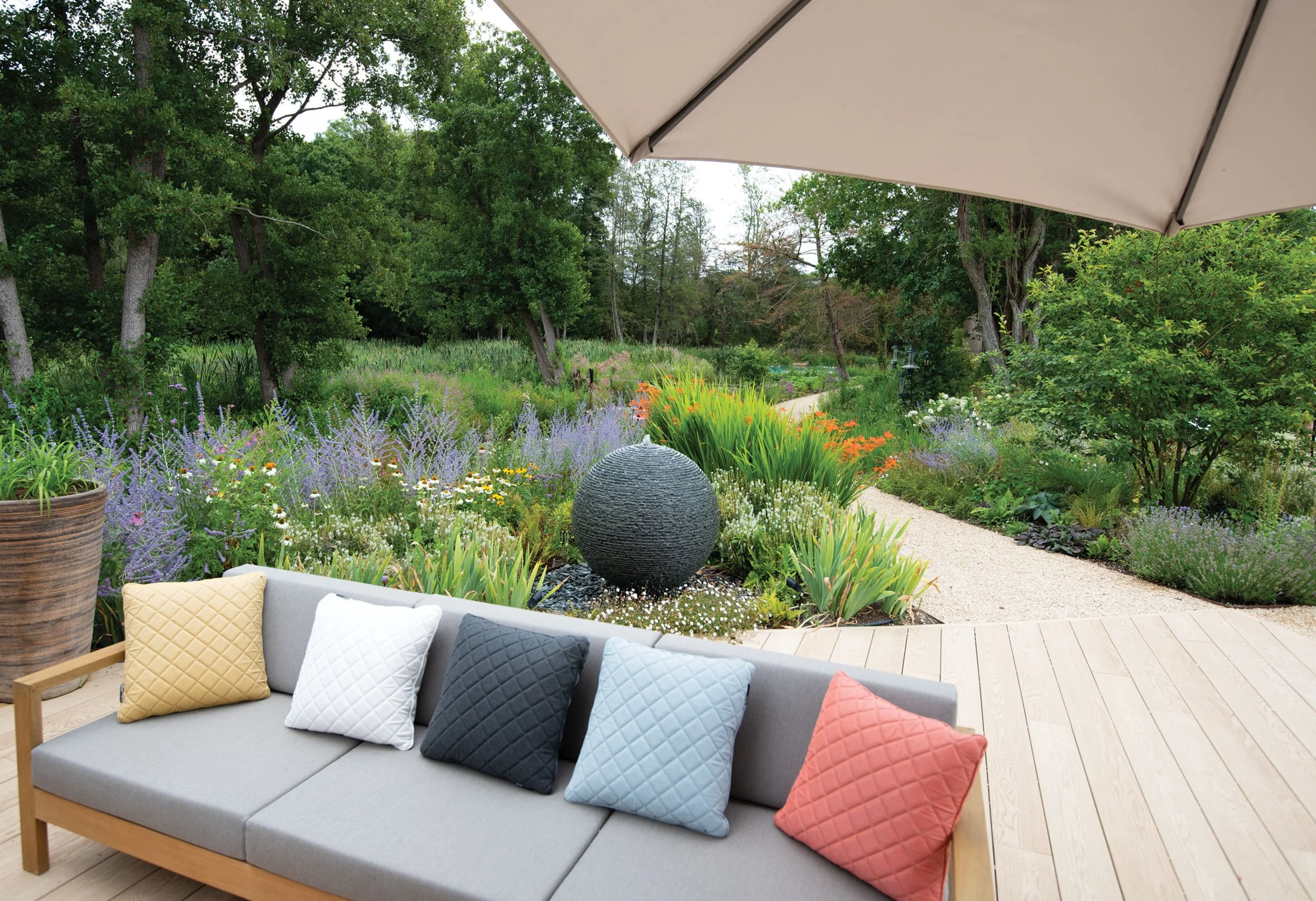 Outdoor seating surrounded by colourful naturalistic planting showing stone water feature, flowing curved beds at The Lake House.