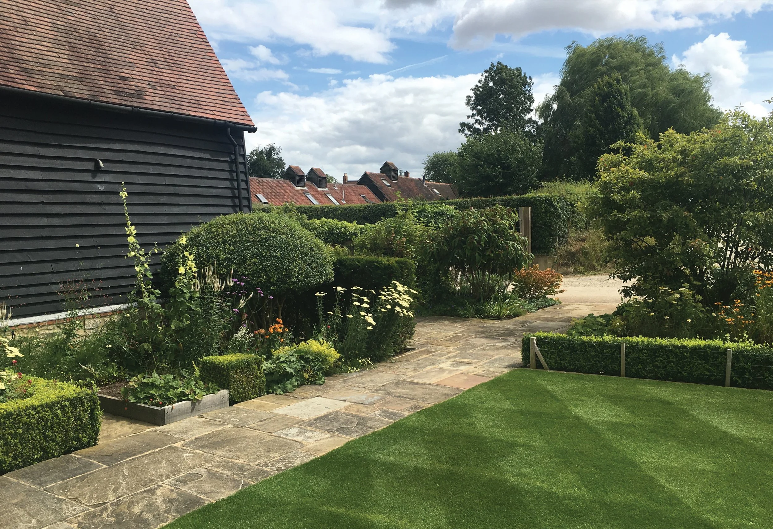 Productive and ornamental planting combined around the family lawn, with specimen Amelanchier, Osmanthus and raised vegetable beds.