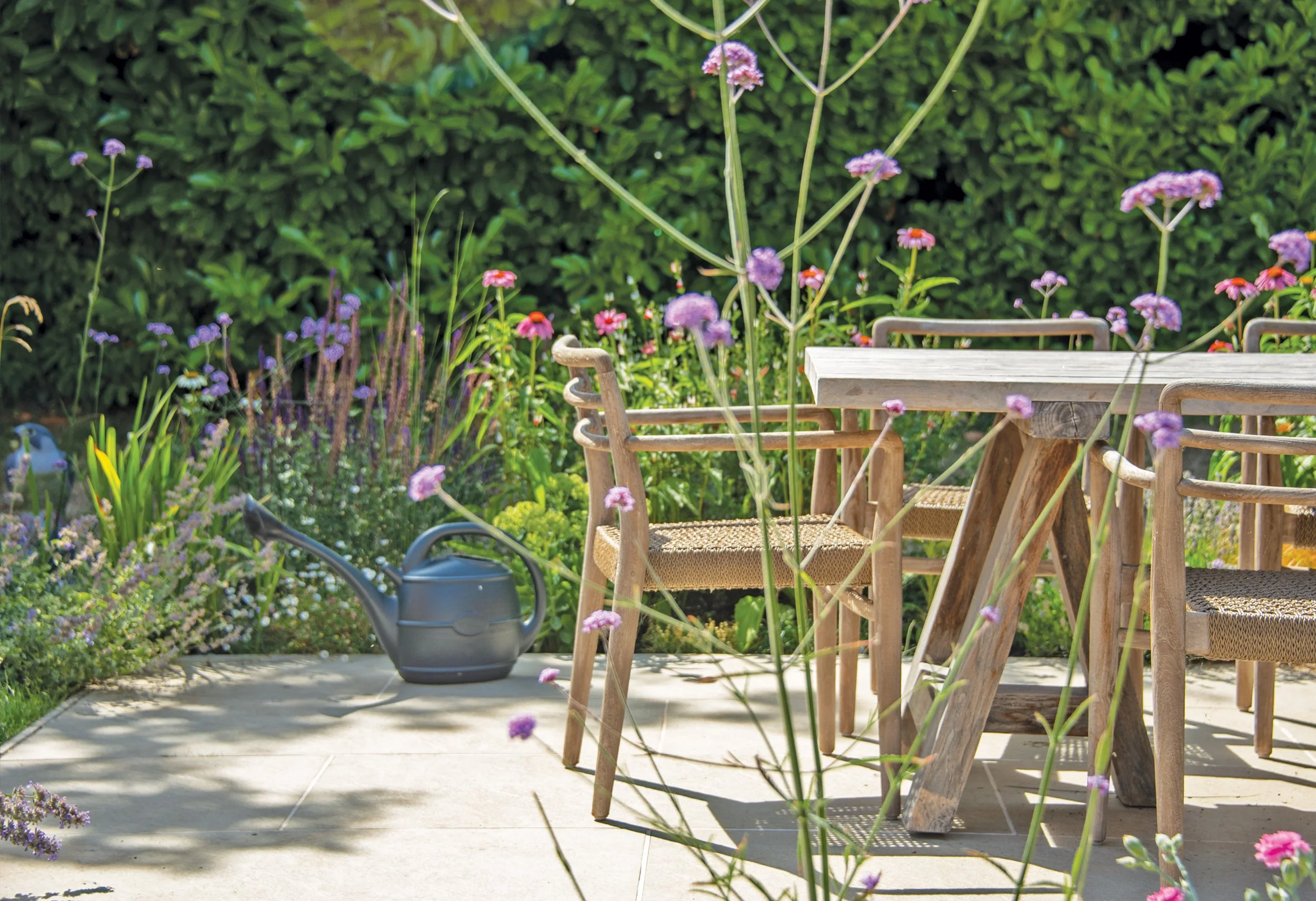 Relaxed outdoor dining area surrounded by Verbena and perennial planting in the family garden.