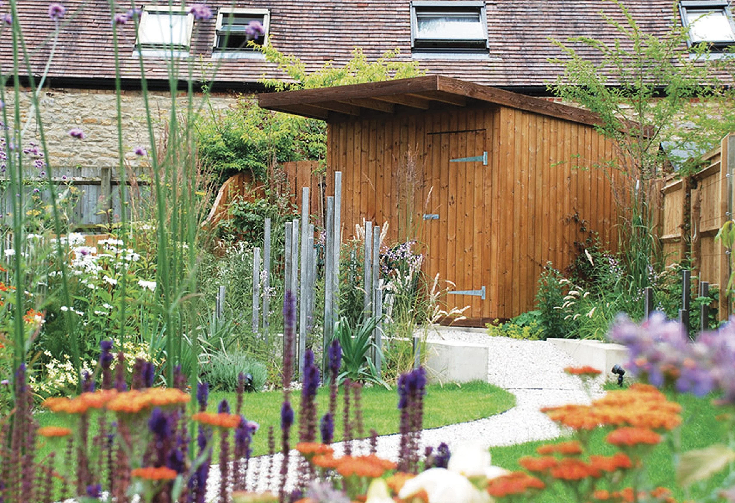 Bespoke shed and sculpture beside vibrant planting.