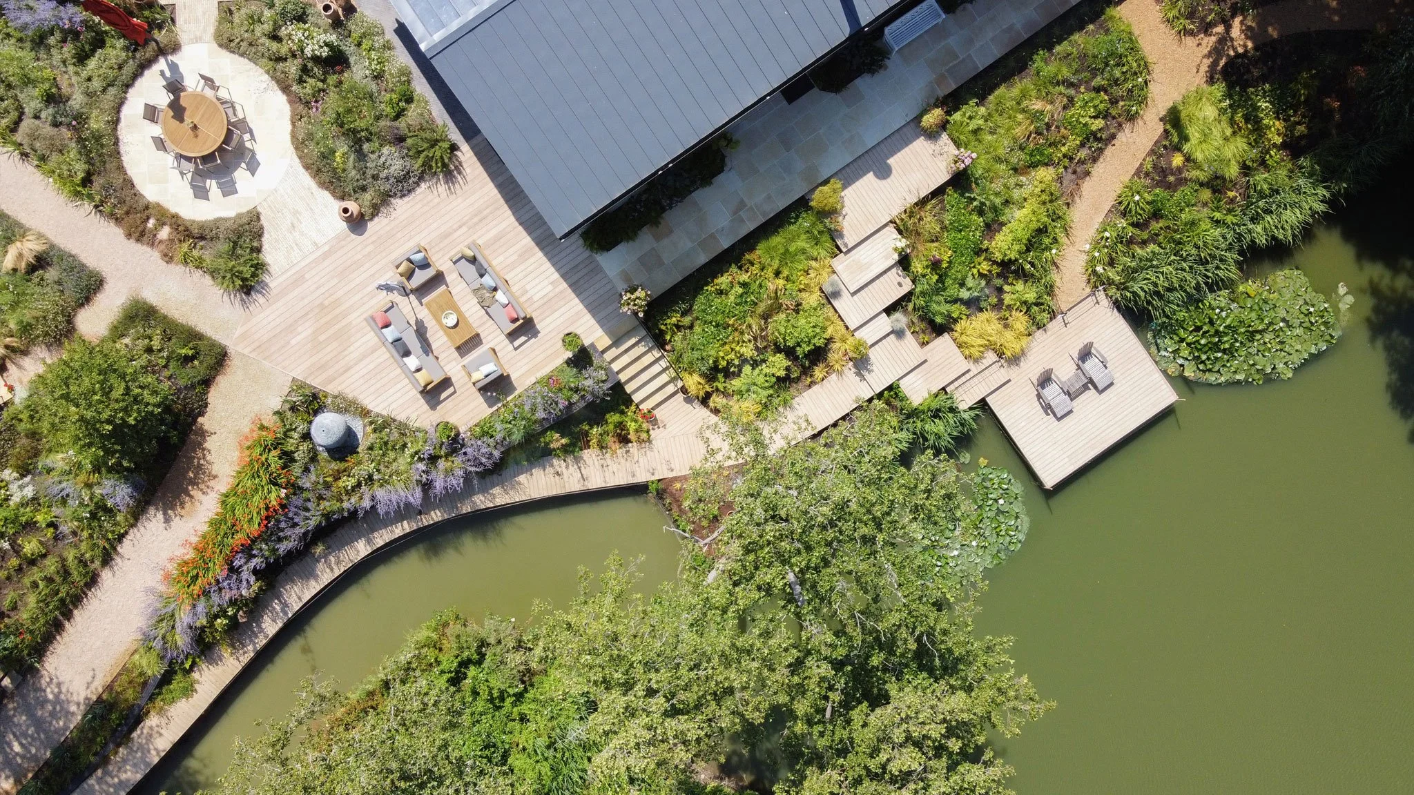 Overhead view of the lakeside terraces, naturalistic planting and timber decks connecting the house with the water.