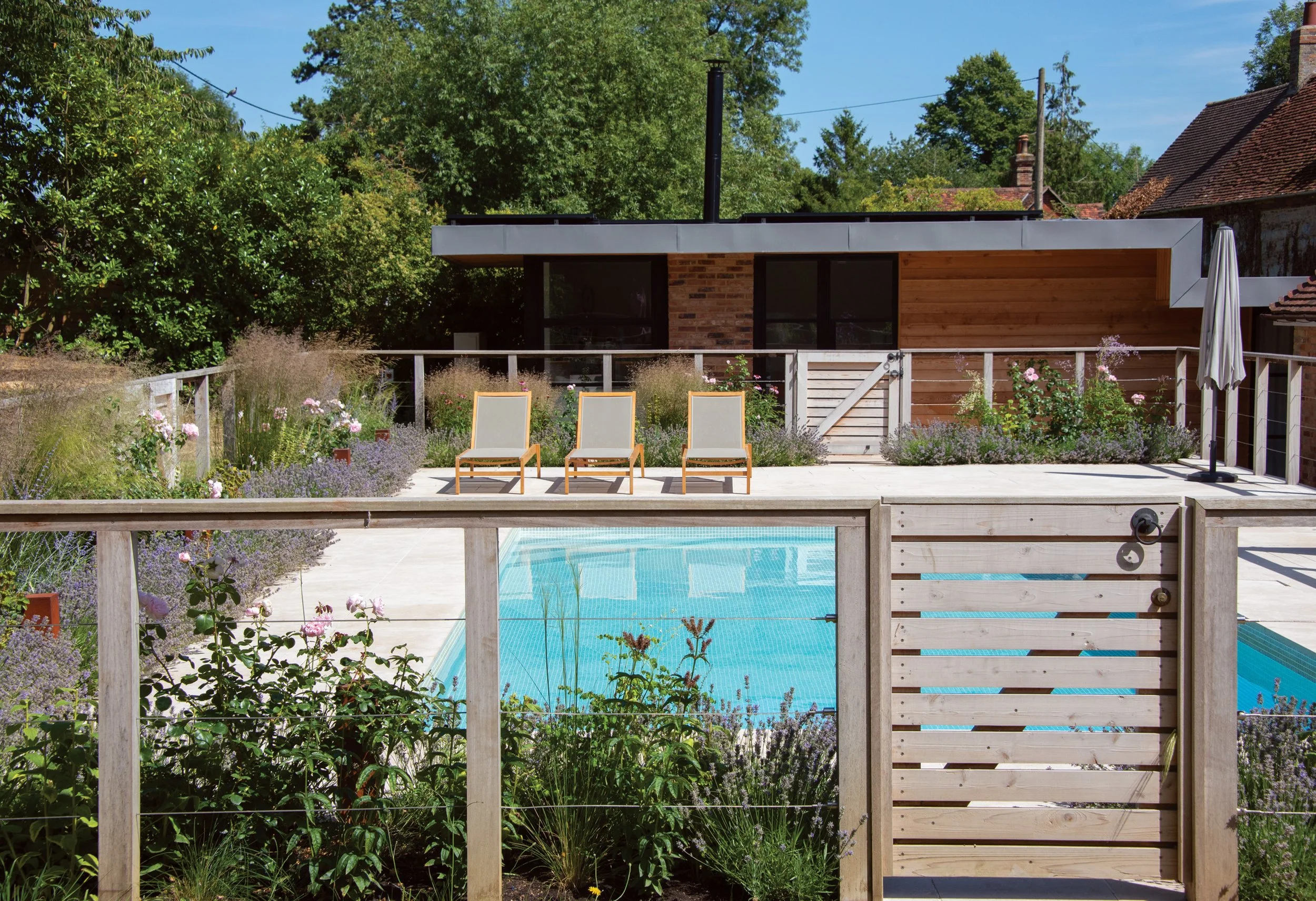 Swimming pool and contemporary garden building framed by naturalistic planting and the new timber enclosure.