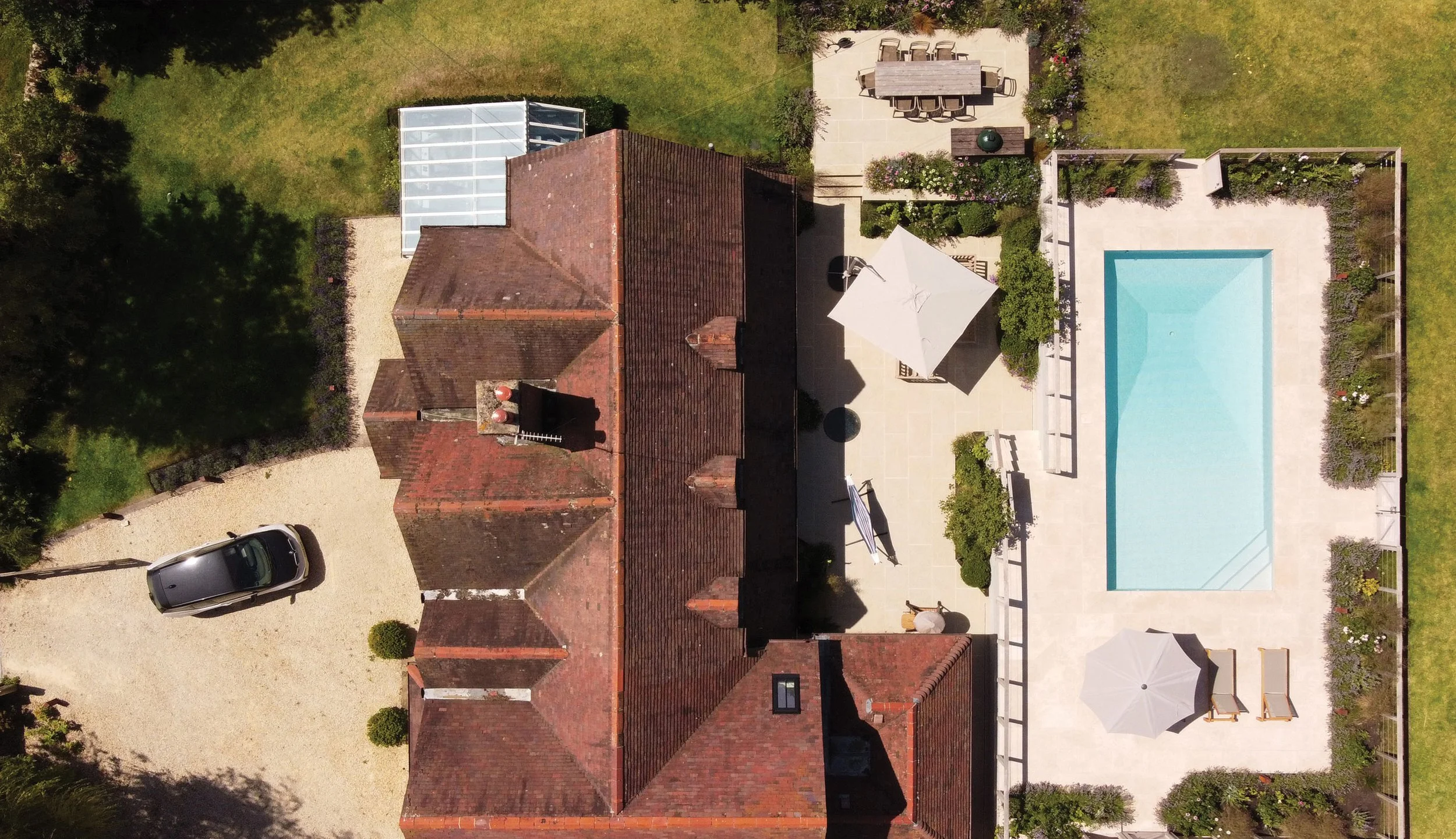 Aerial view of The Courtyard Pool Garden in Marsh Baldon, Oxfordshire, showing the renovated house, swimming pool and family terraces.