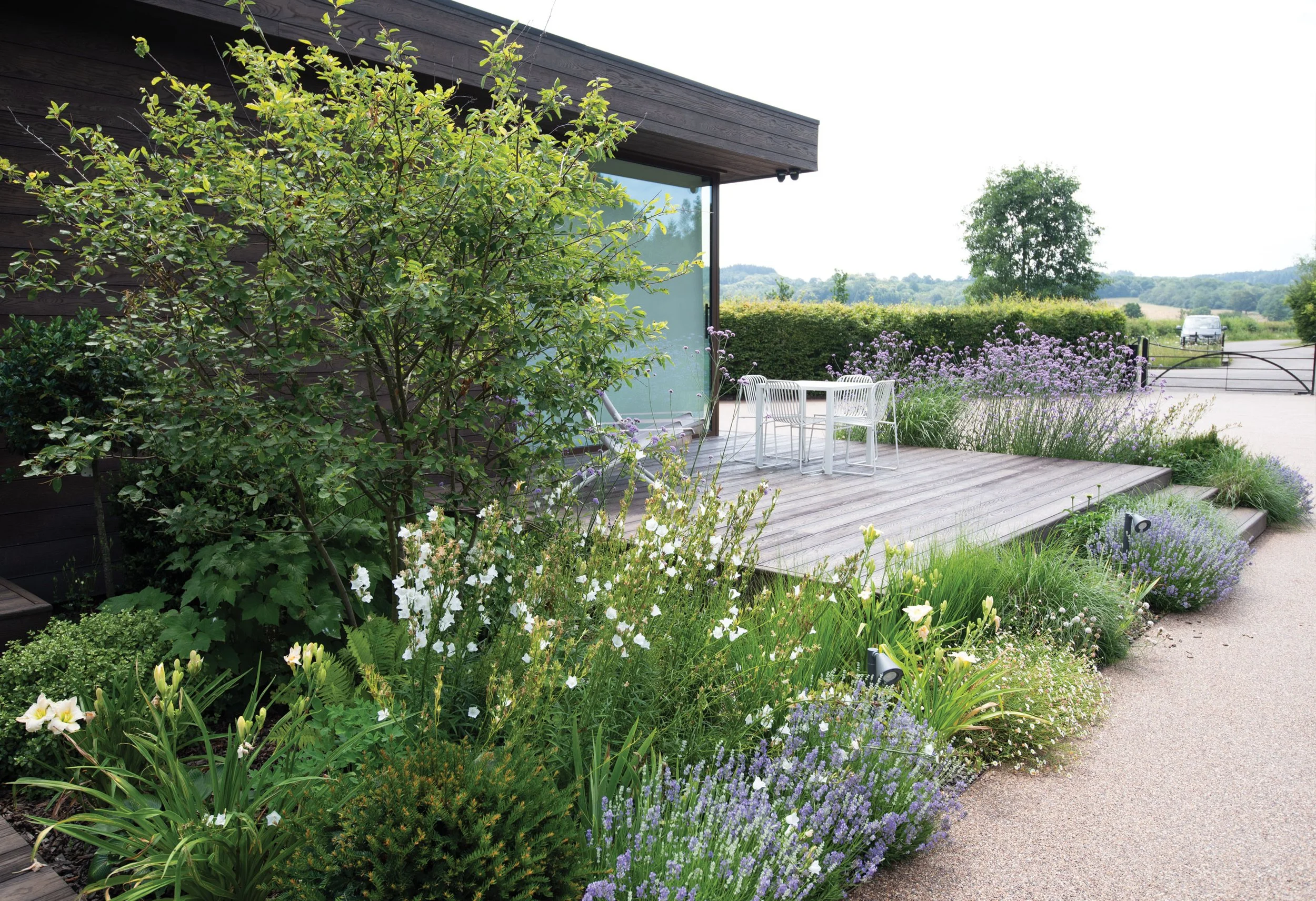 Amelanchier tree and relaxed perennial planting surrounding a private timber terrace with views across the Surrey countryside.