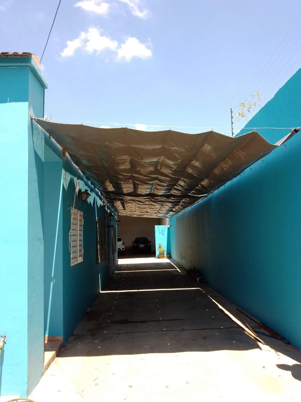 Toldo corredizo de lona de PVC color gris instalado en galería, sistema sobre rieles de alambre.