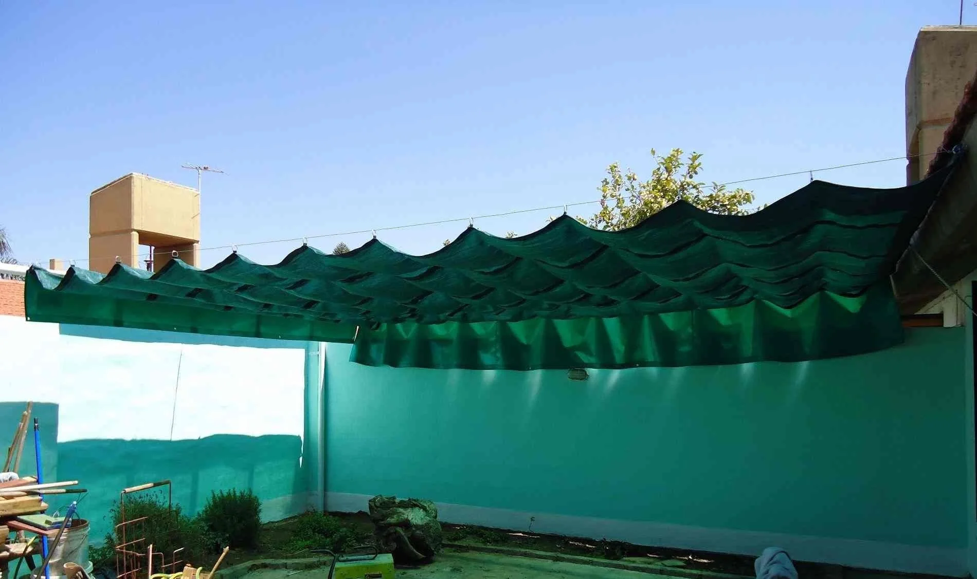 Sombra exterior con toldo corredizo en patio techado, lona mediasombra, ideal para días soleados.