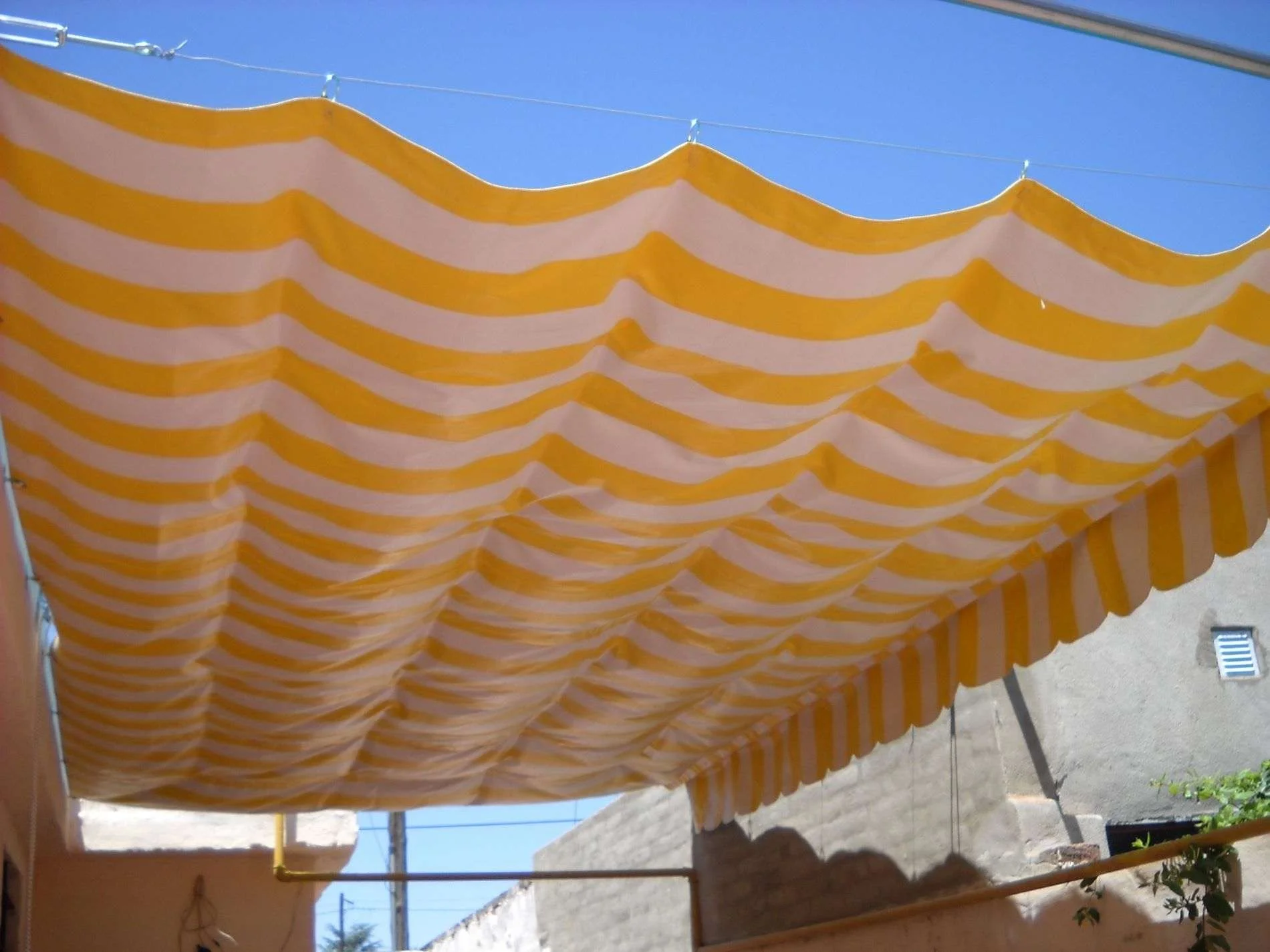 Toldo corredizo decorativo para jardín con lona textil, ideal para uso en verano.