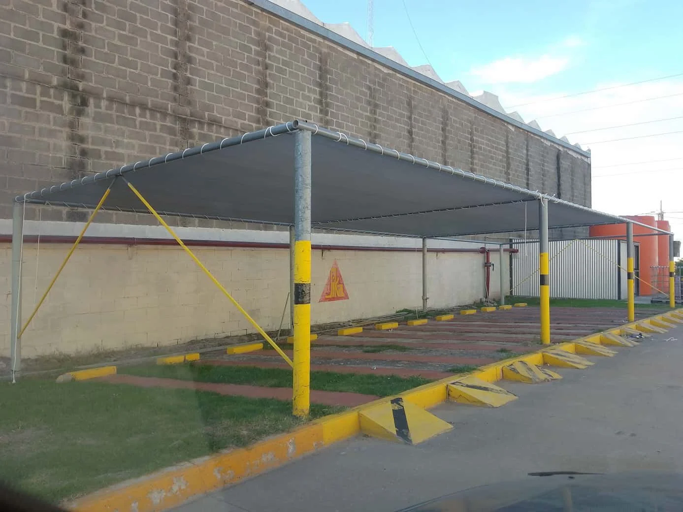 Cobertura de lona impermeable color gris instalada en estructura metálica para vehículos.