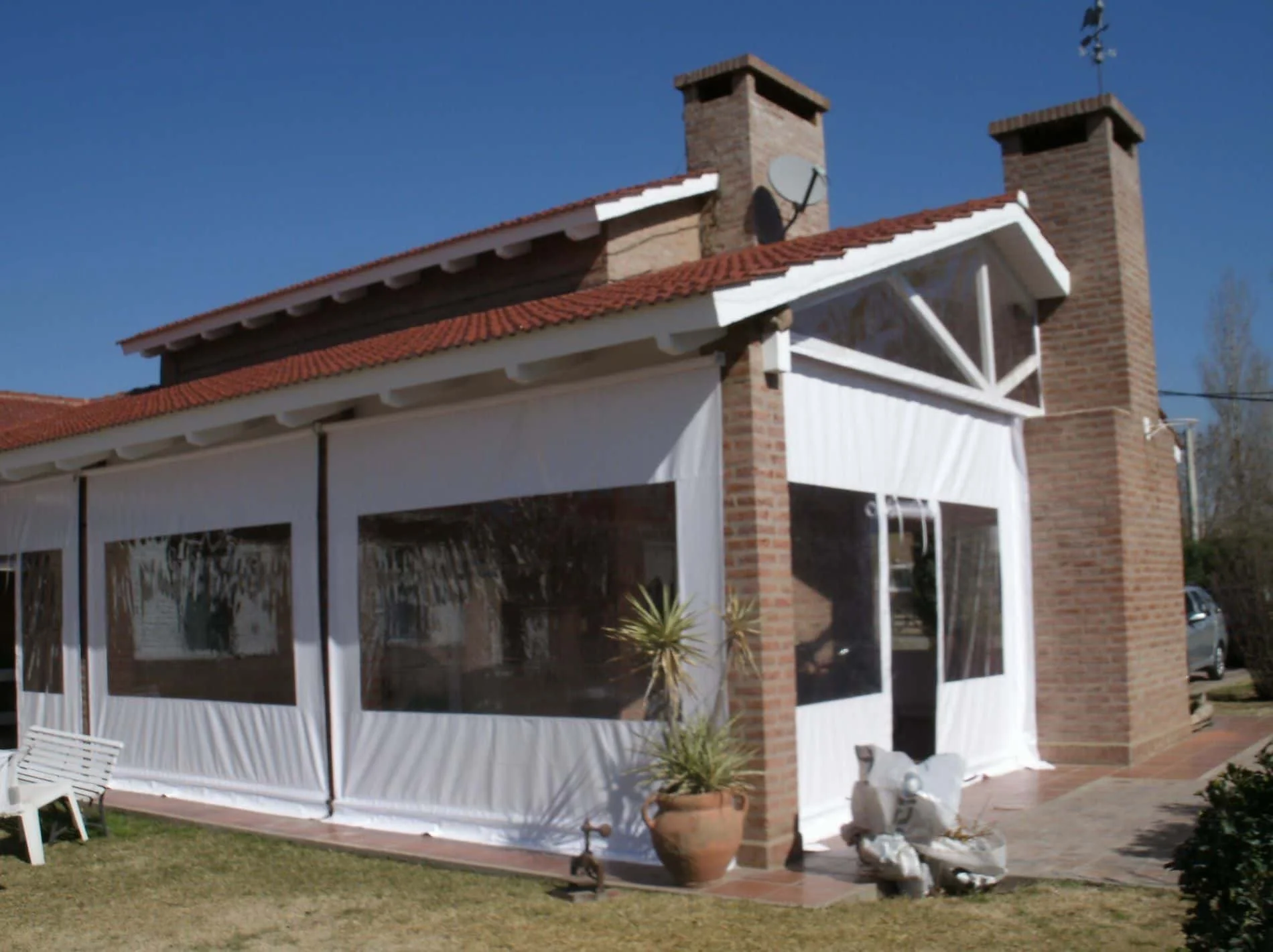 Cerramiento con cortinas levadizas de lona PVC en galería, protección contra sol y viento.