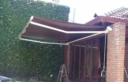 Toldo brazo invisible color gris con brazos metálicos reforzados, ideal para protección solar en patios.
