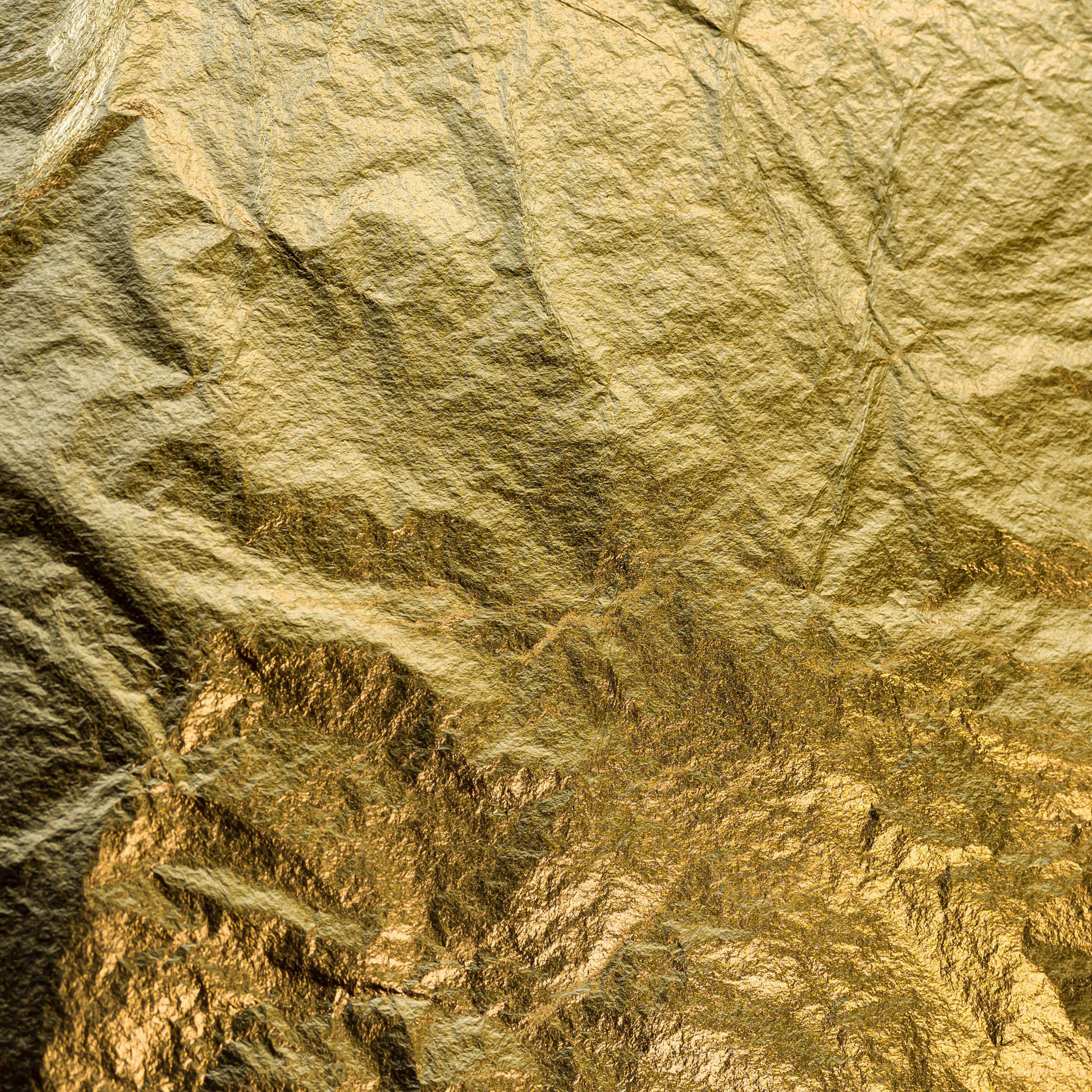 Close-up of a crumpled gold-colored foil surface with textured wrinkles and creases.