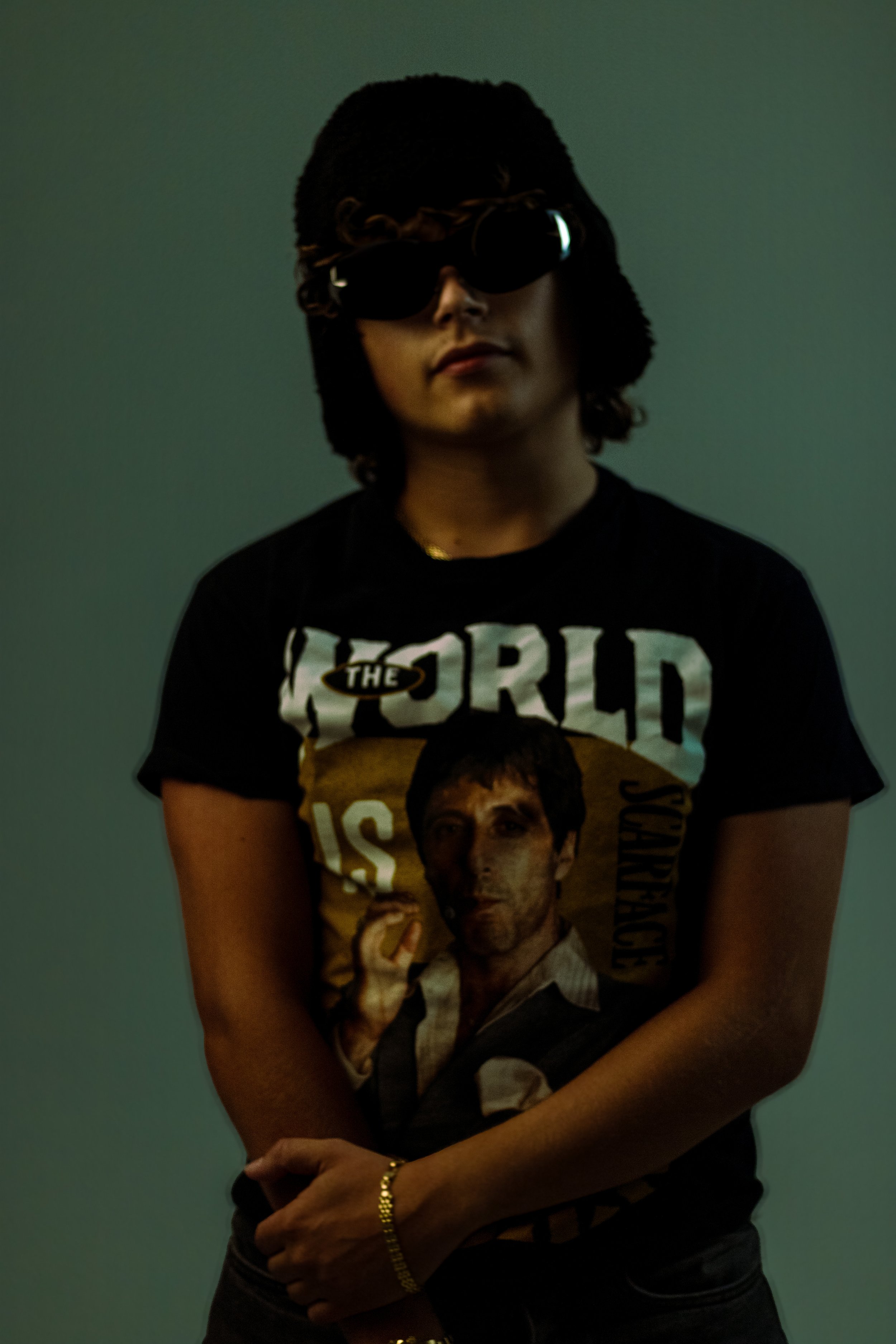 Person wearing large black sunglasses and a black T-shirt featuring a portrait of a man making a thumbs-up gesture.
