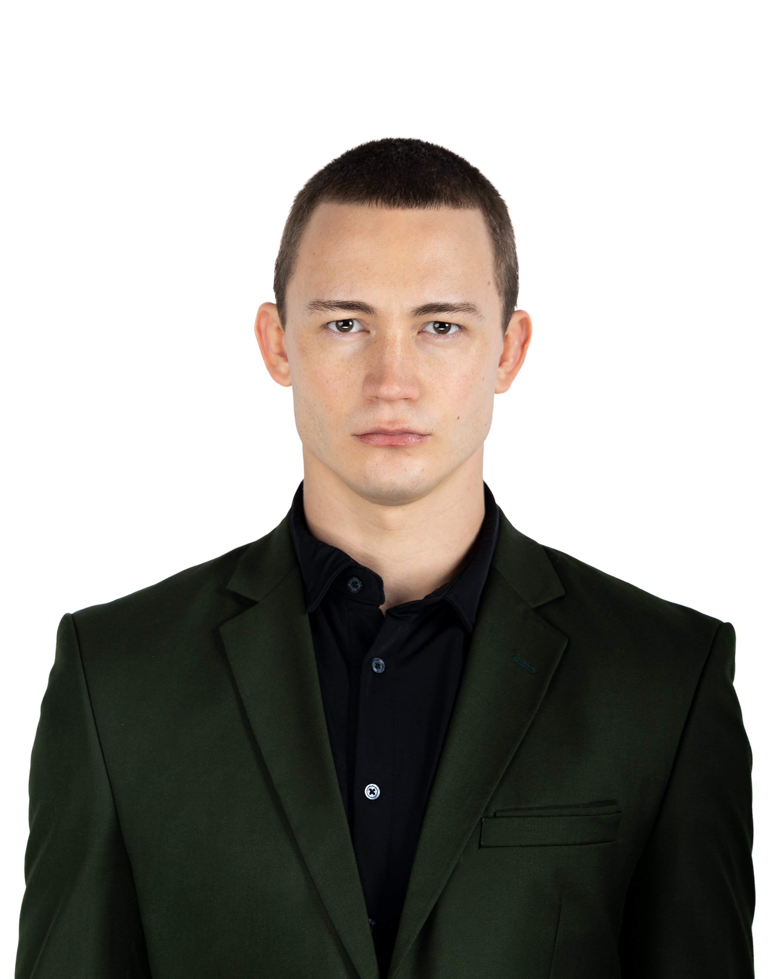 Close-up of a young man with short dark hair, fair skin, wearing a black shirt and a dark green blazer, against a white background.