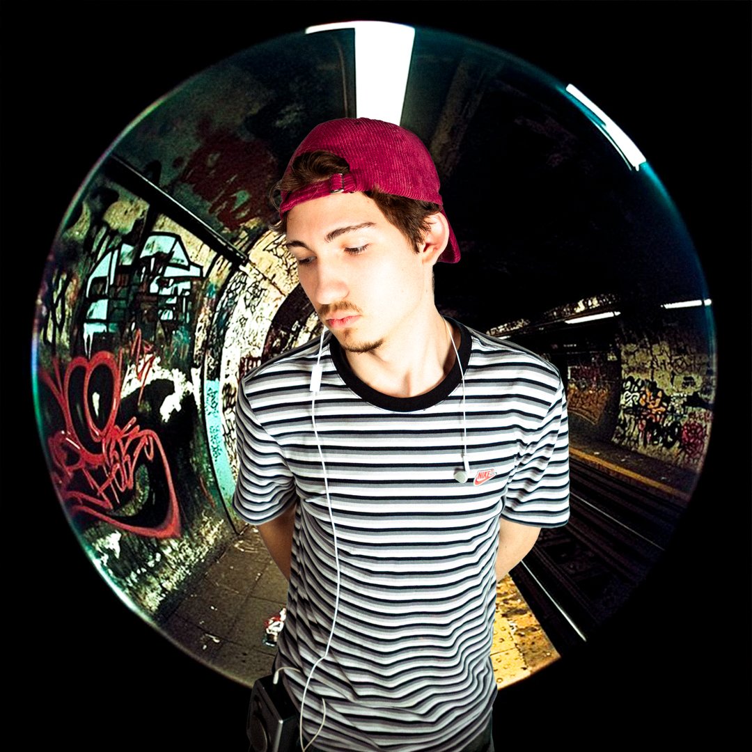 Teenage boy in striped t-shirt, red cap backwards, with earphones, standing in a graffiti-covered tunnel, captured with a fisheye lens.