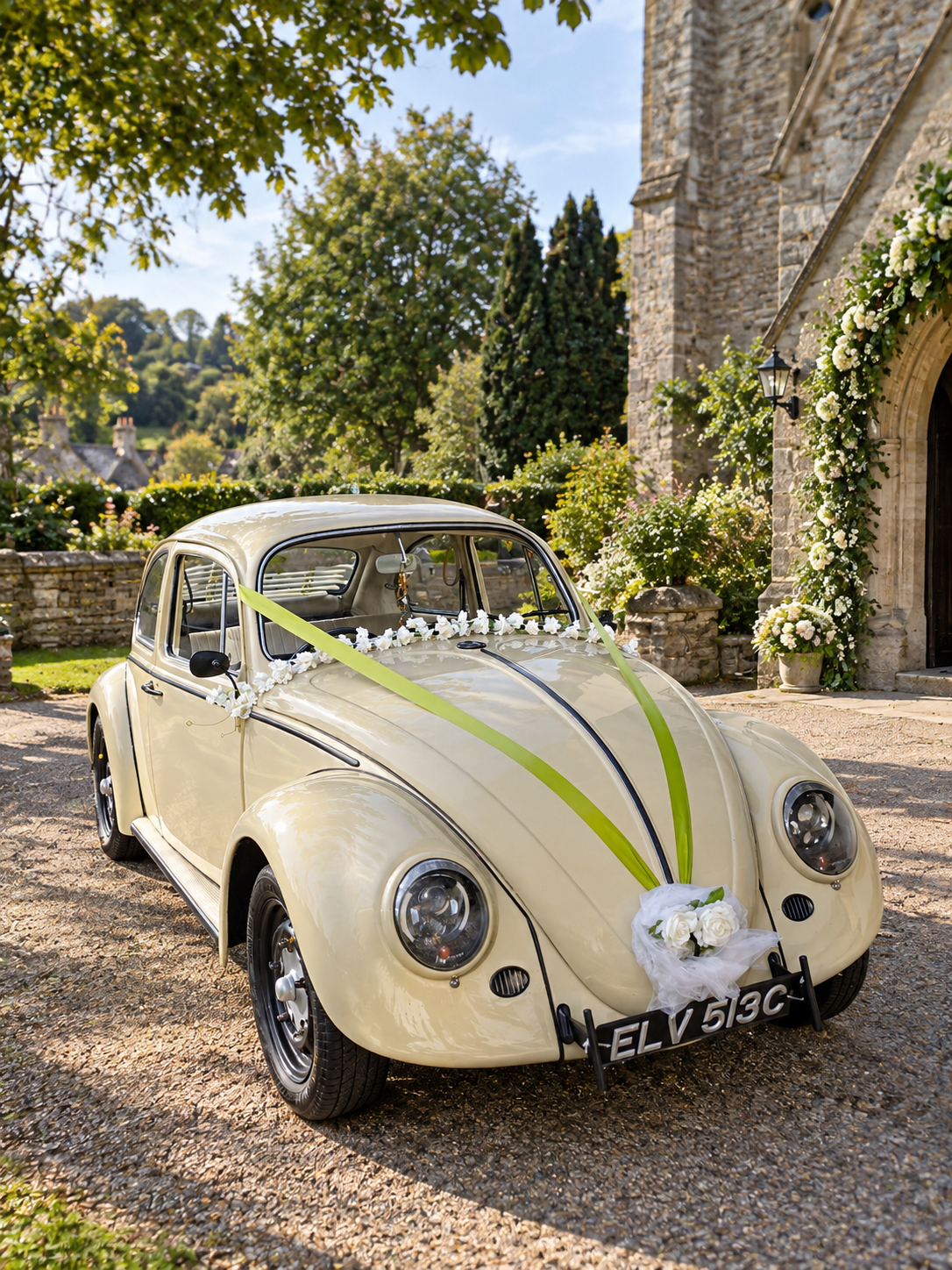 Elvis, our cream vintage VW Beetle wedding car with green ribbons, outside a Devon church