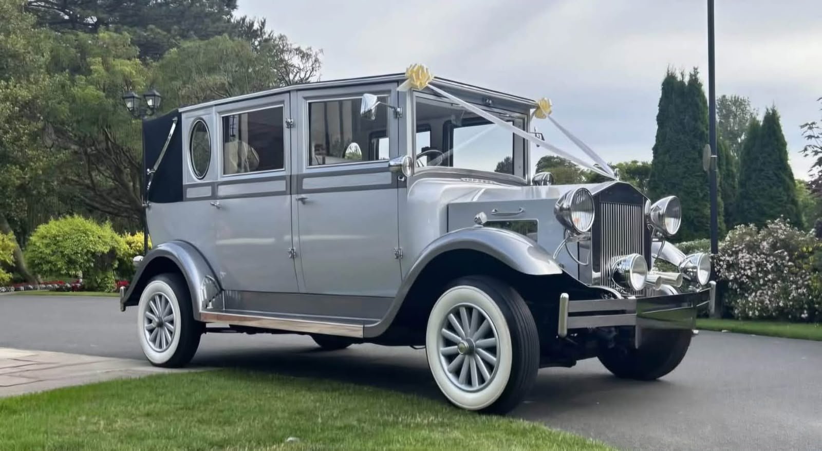Silver Imperial 8-seater vintage wedding car with white ribbons in Devon