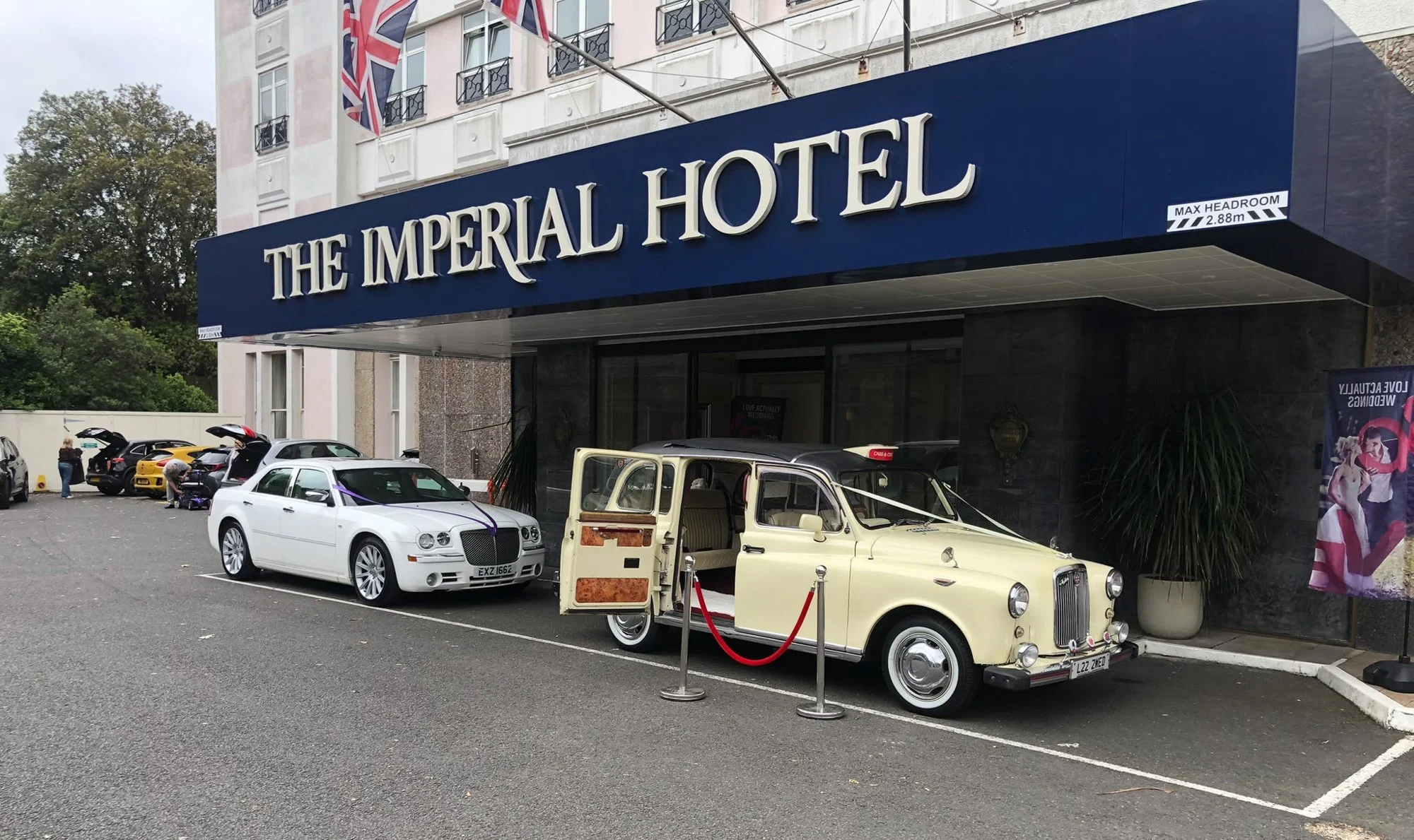 Cream London cab and white Chrysler Baby Bentley wedding cars outside The Imperial Hotel, Torquay