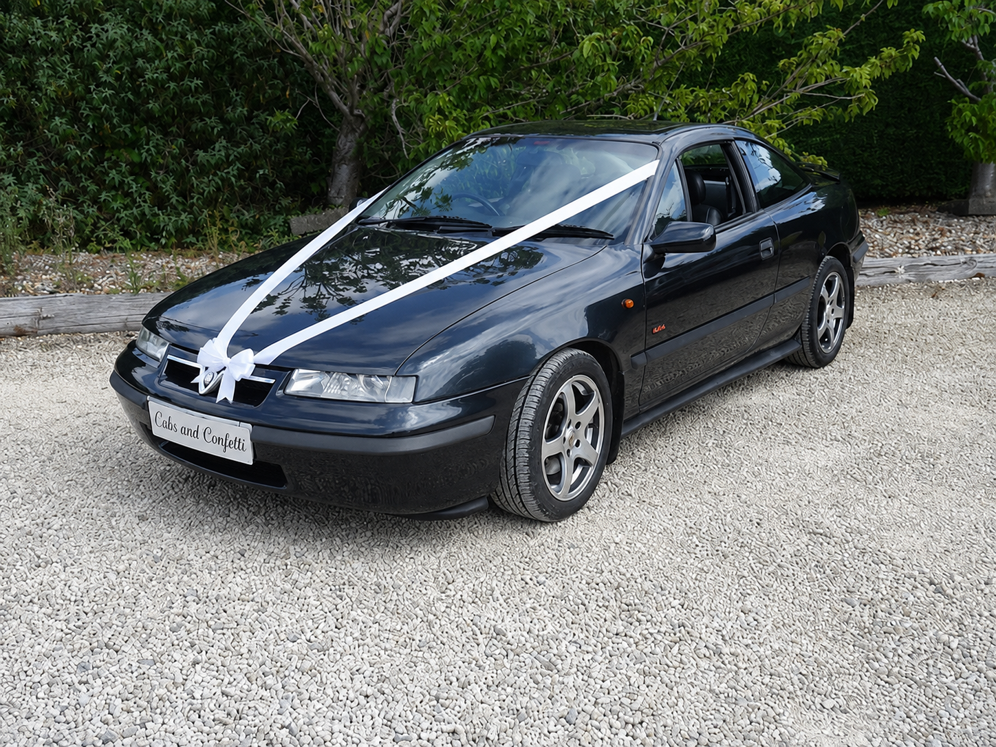 Black Vauxhall Calibra wedding car dressed with white ribbons