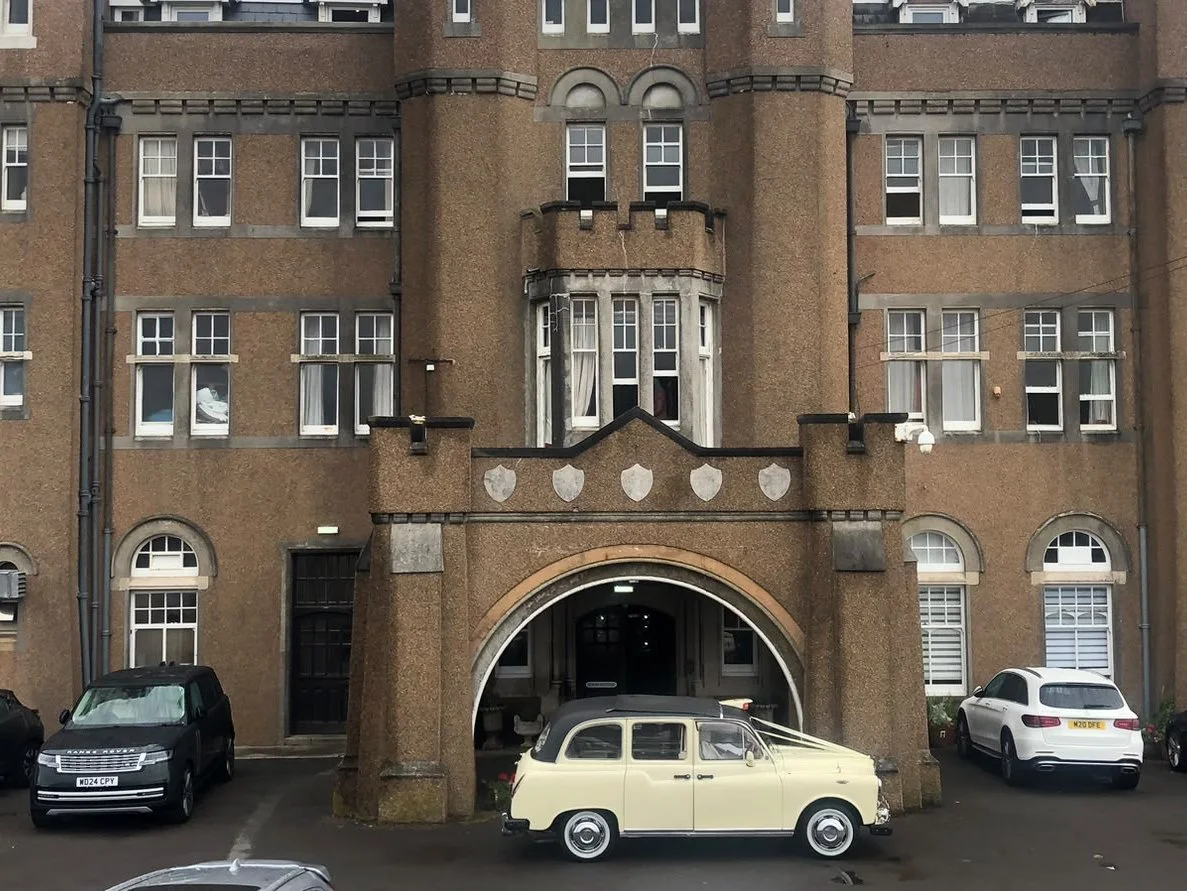 Cream London cab wedding car outside a castle wedding venue in Devon