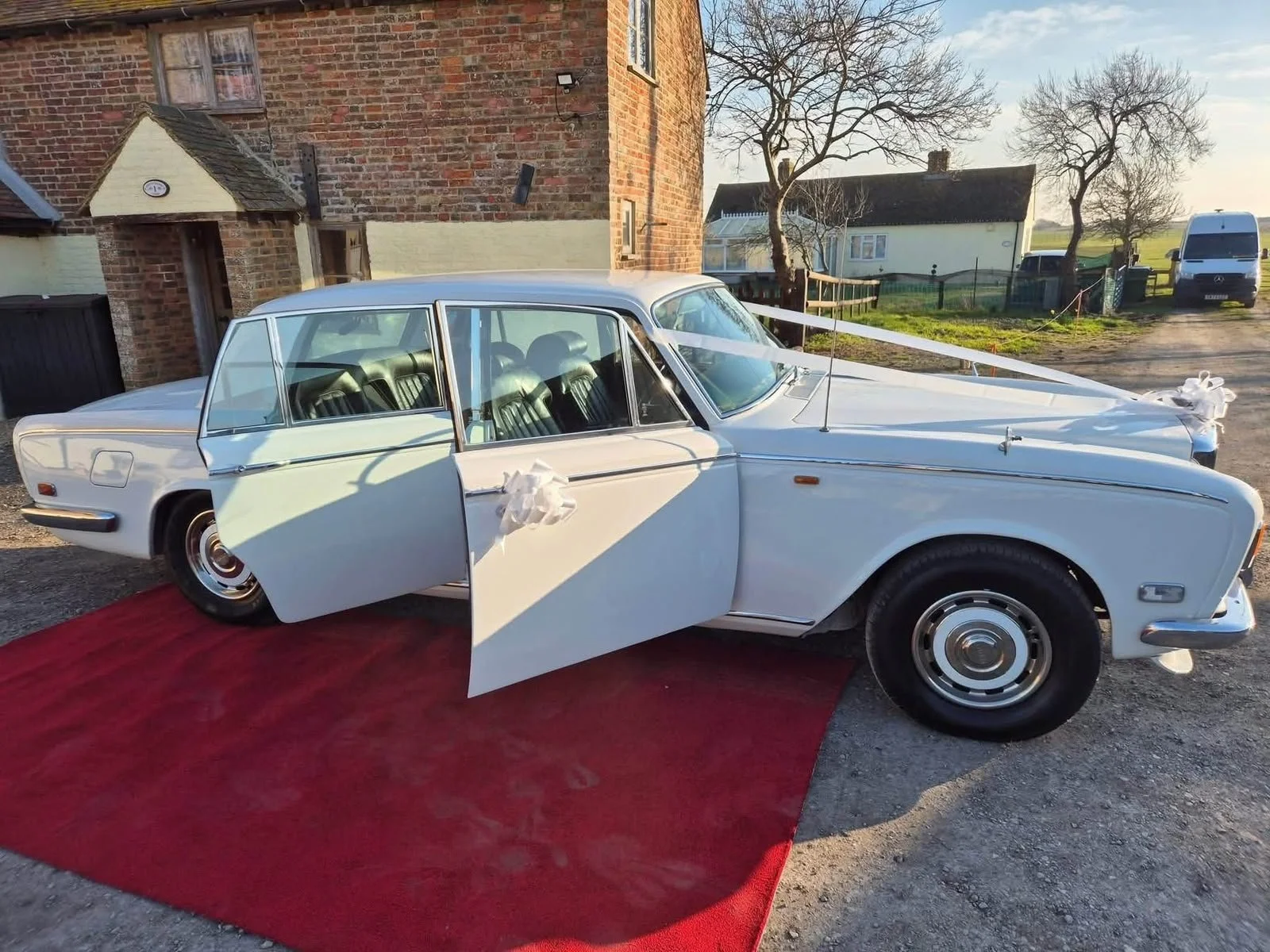 White Bentley T2 wedding car with ribbons on a red carpet in Devon