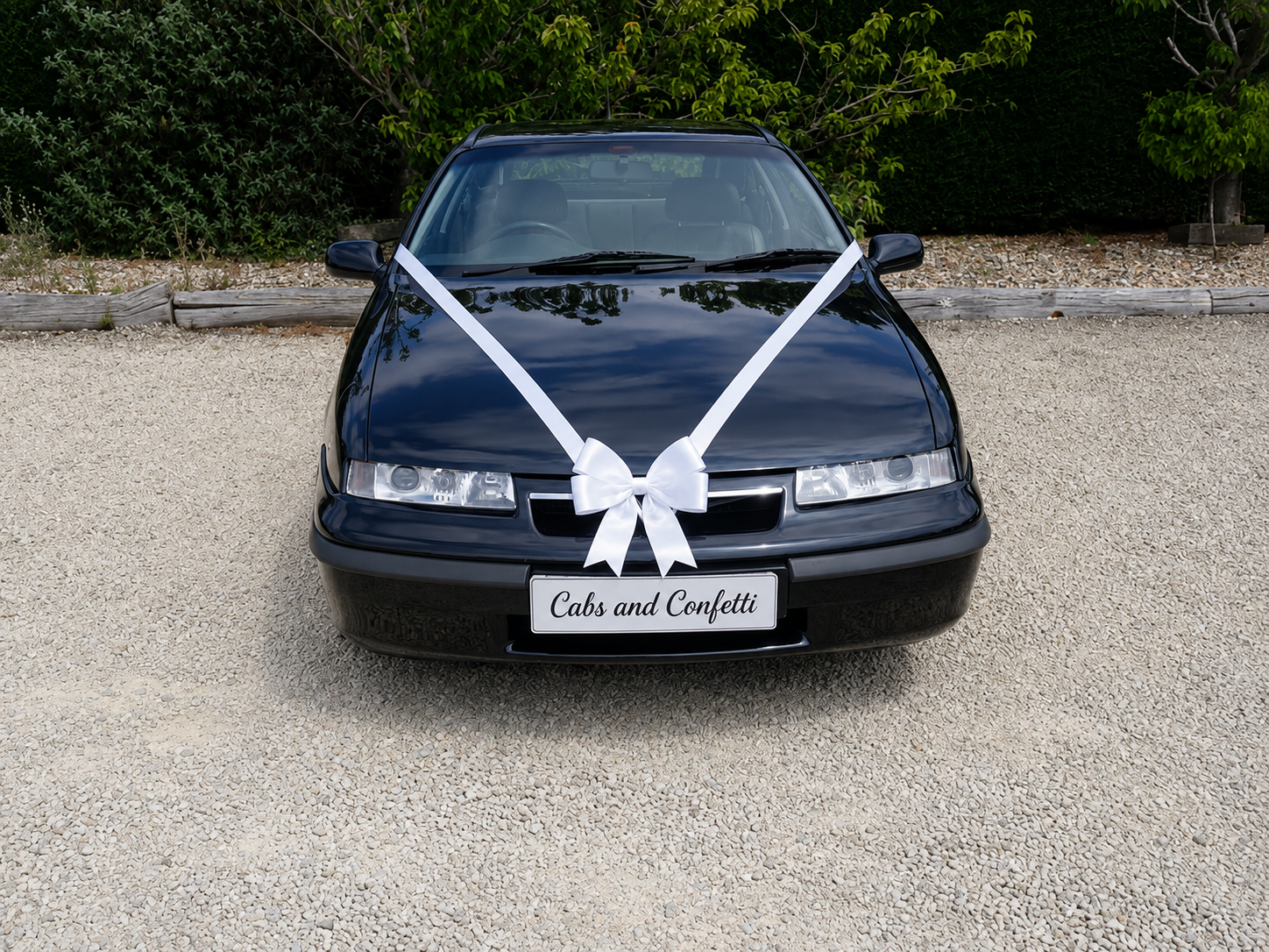 Front of the black Vauxhall Calibra wedding car with a white bow