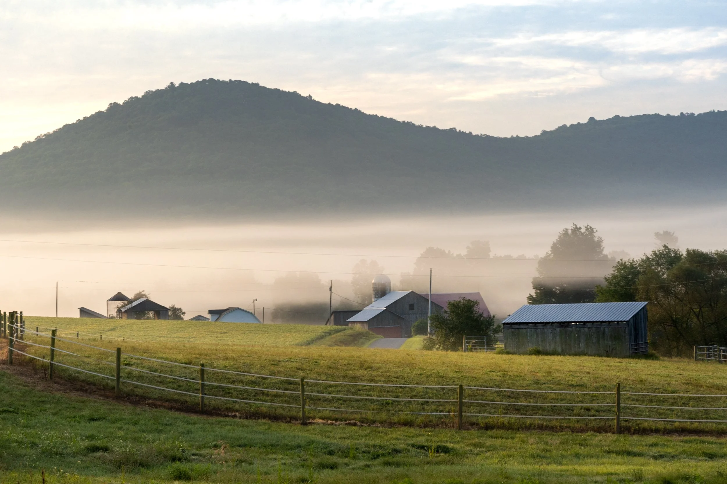"September Serenade"

A tranquil composition that captures a farmstead's stillness in the tender embrace of early morning light. As the dawn unfurls its misty shroud over the landscape, each element of rural life—the empty corn crib, the steadfast ba