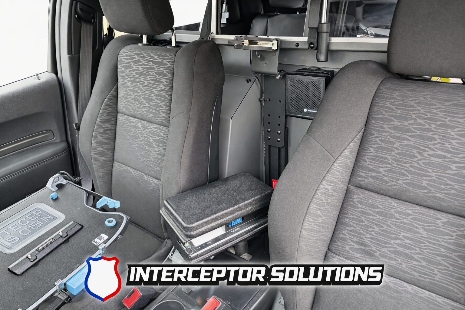 Interior of a police vehicle with two seats, various equipment, and an Interceptor Solutions logo at the bottom.
