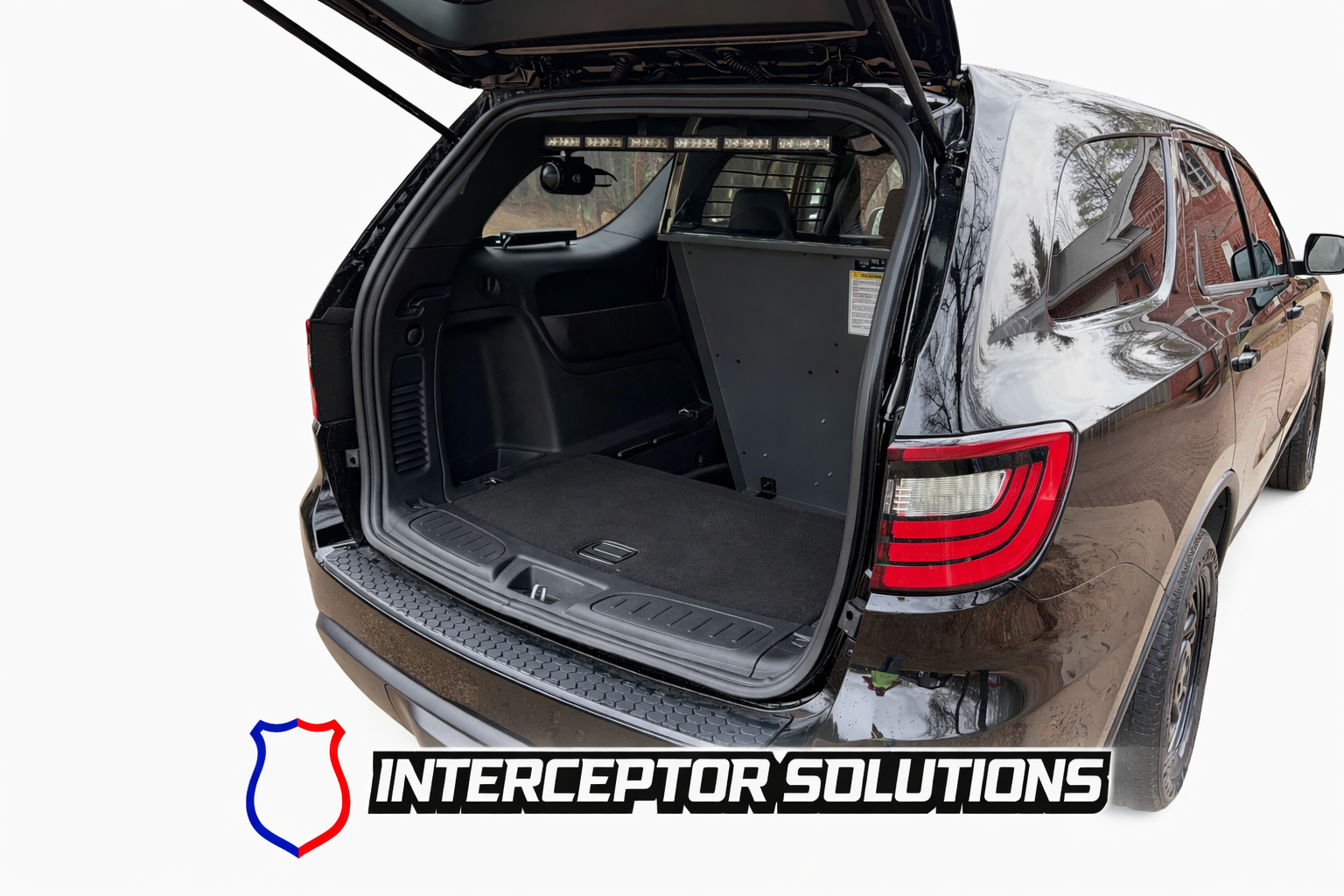 Open trunk of a black SUV showing a partition inside, with a logo of a shield divided into red and blue sections and the text 'Intercepter Solutions' underneath.