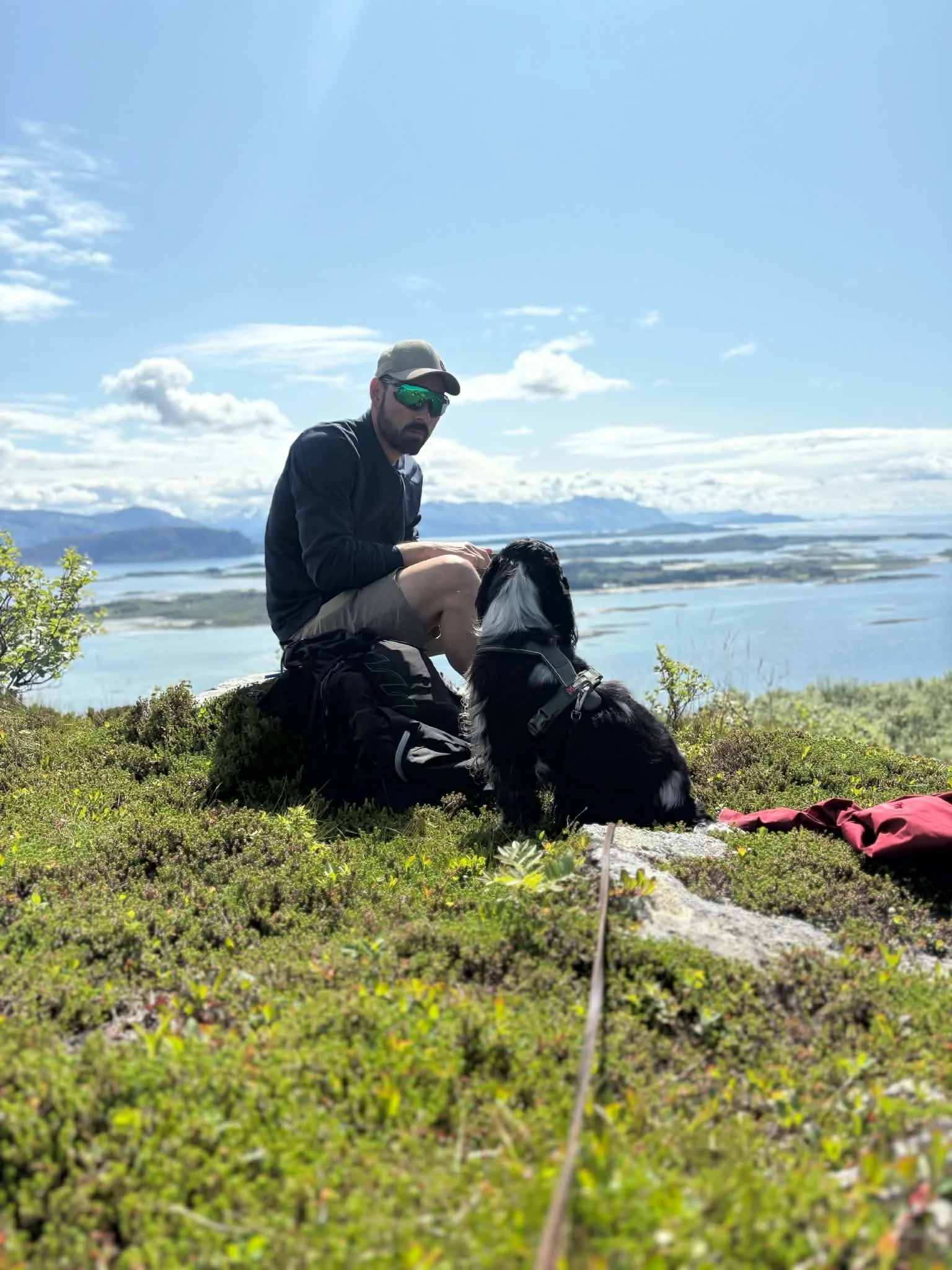 Cocker spaniel og mann som sitter med havet i bakgrunn
