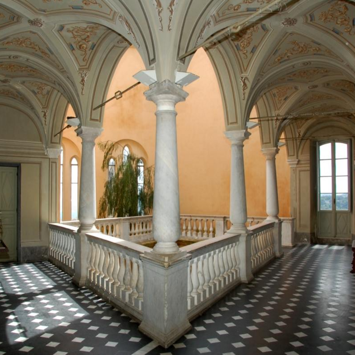 Galerie intérieure du château Grimaldi avec colonnes, voûtes décorées et sol à motifs géométriques.