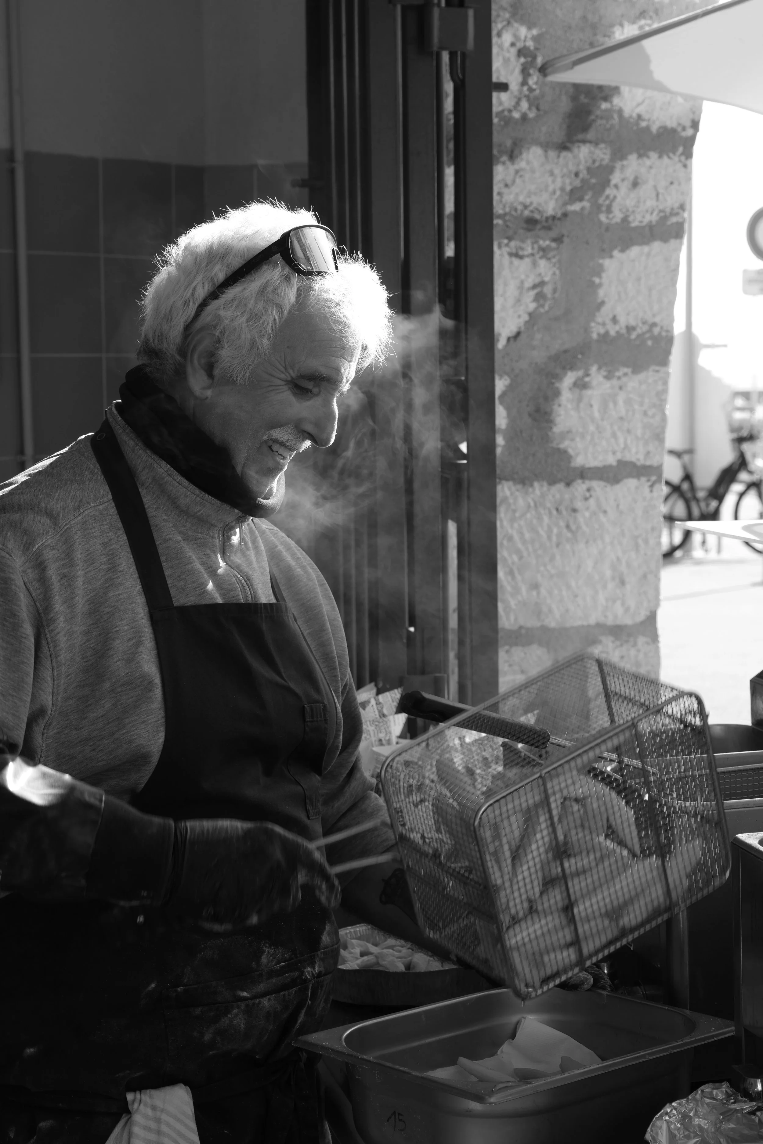 Poissonnier en tablier préparant des fritto misto une  dans une ambiance artisanale en noir et blanc.