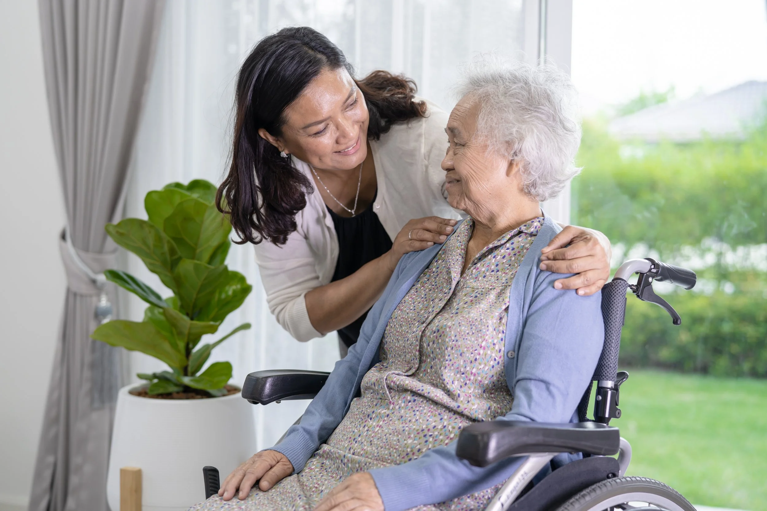 Woman in wheelchair smiling at caregiver