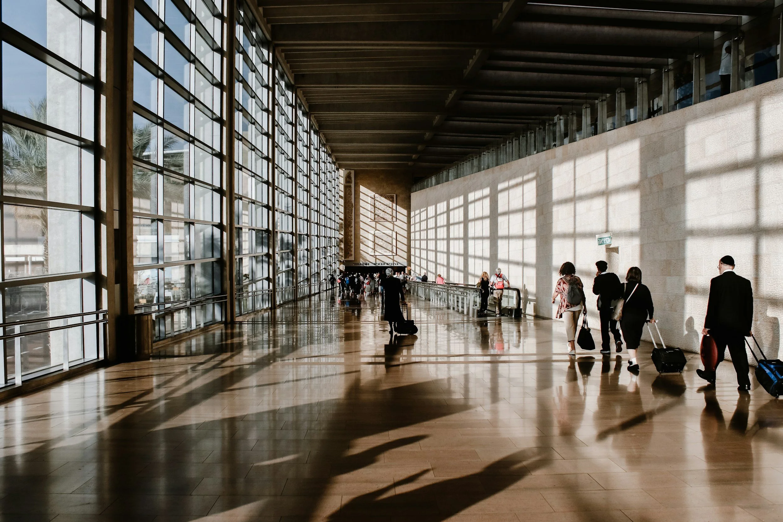 A long hall at an airport with travelers walking through it